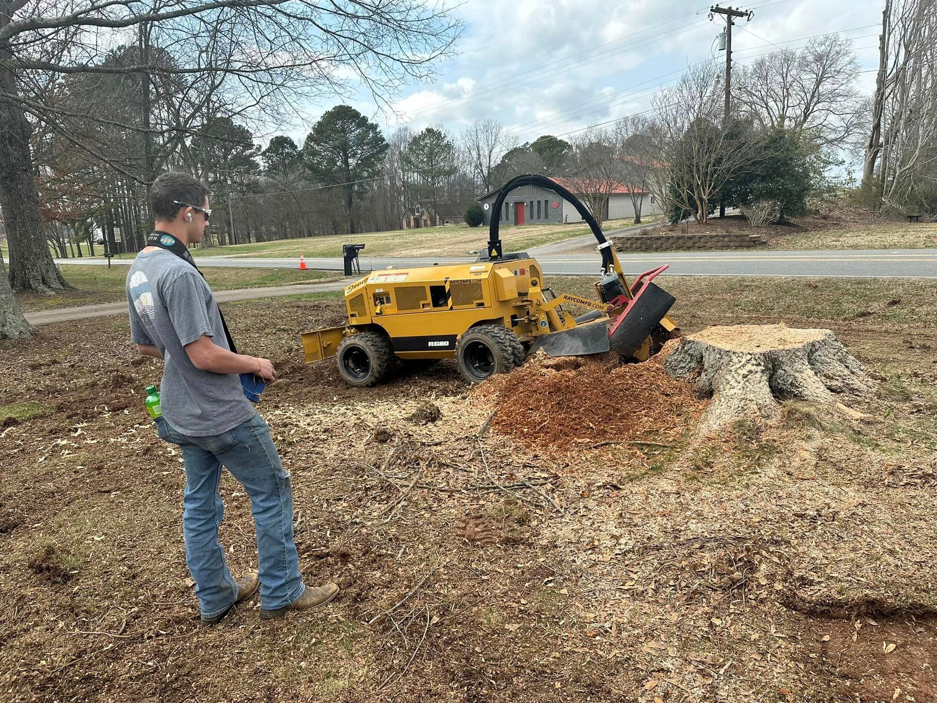A man is standing in front of a stump grinder.