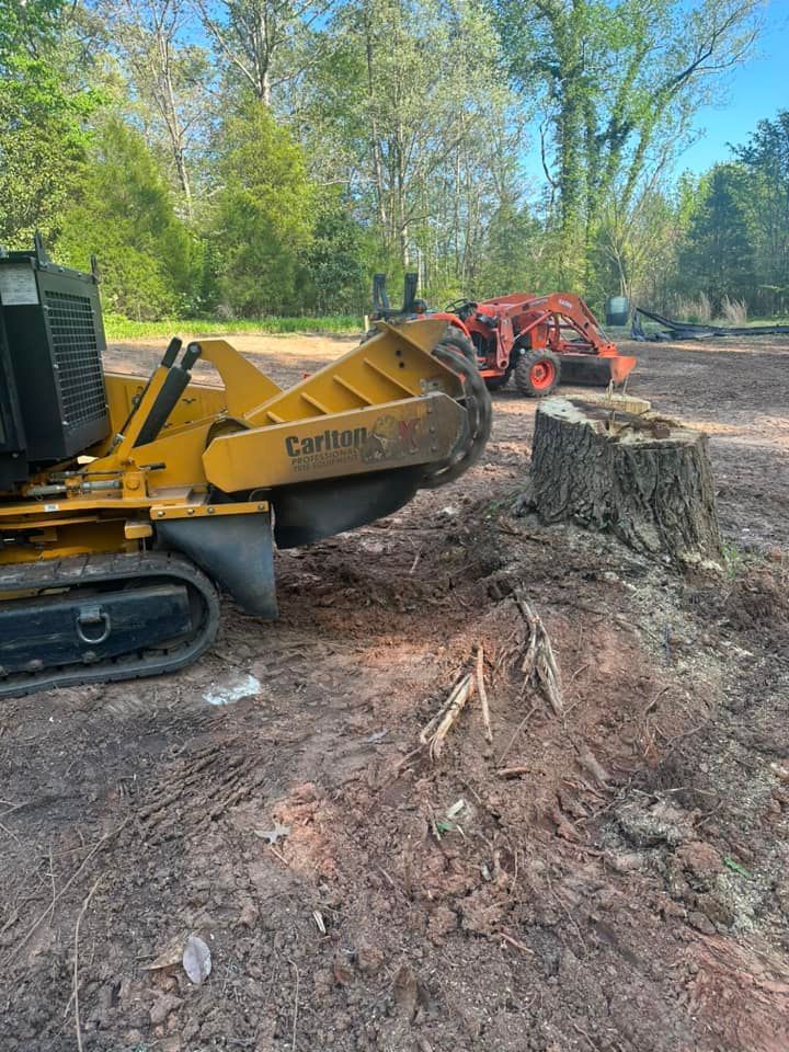 A stump grinder is cutting a tree stump in a dirt field.