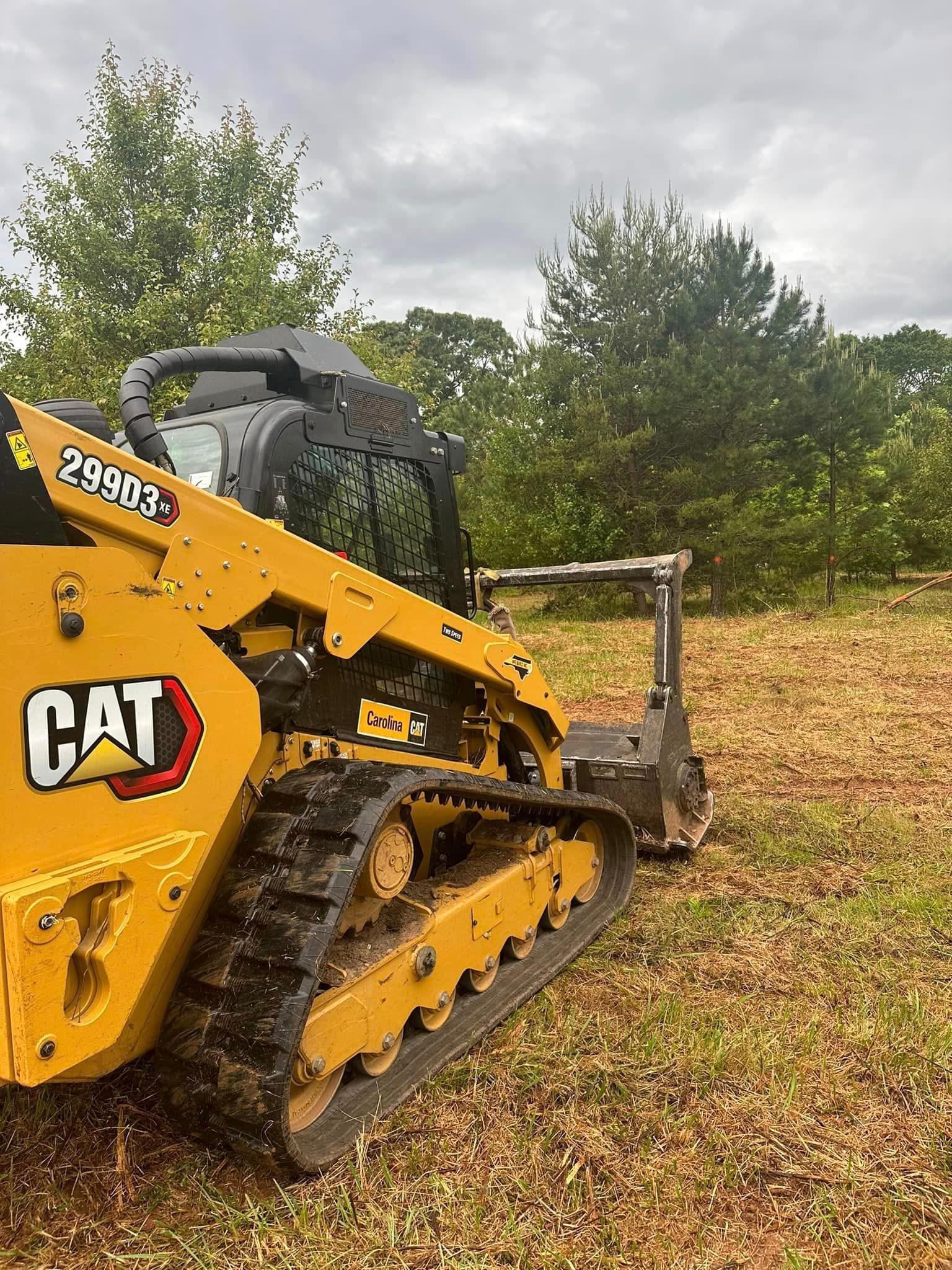 A yellow cat bulldozer is sitting in the middle of a field.