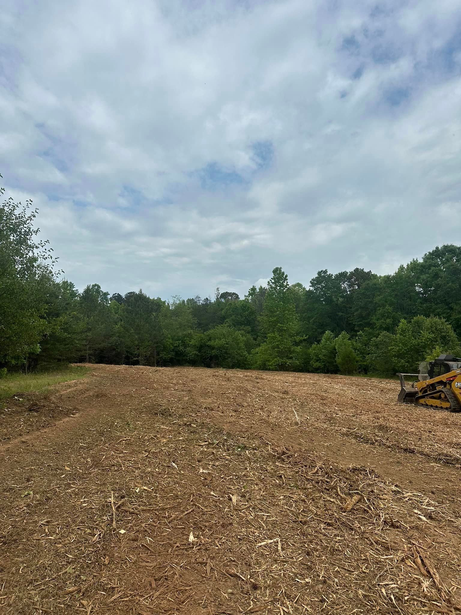 A tractor is driving through a field of wood chips.