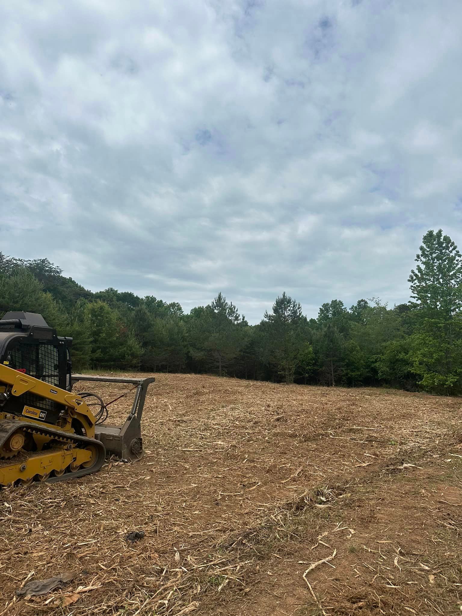 A bulldozer is sitting on top of a pile of wood chips in a field.