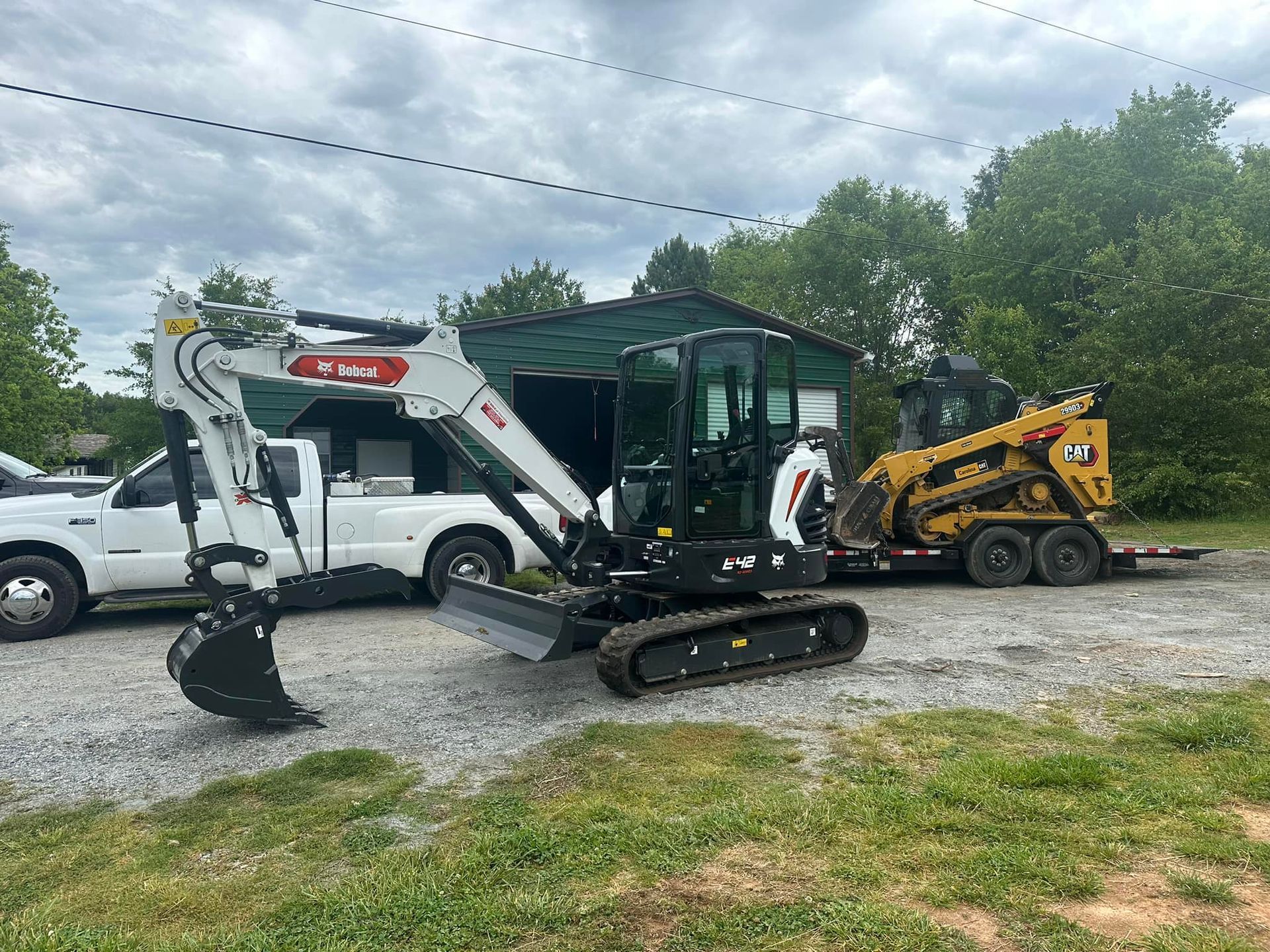 A small excavator is parked next to a white truck.