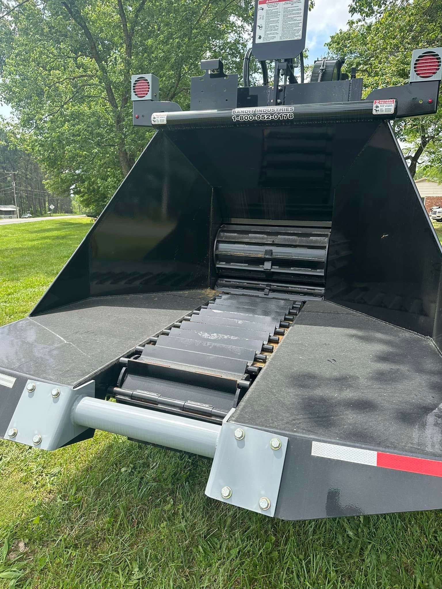 A large black machine is sitting on top of a lush green field.