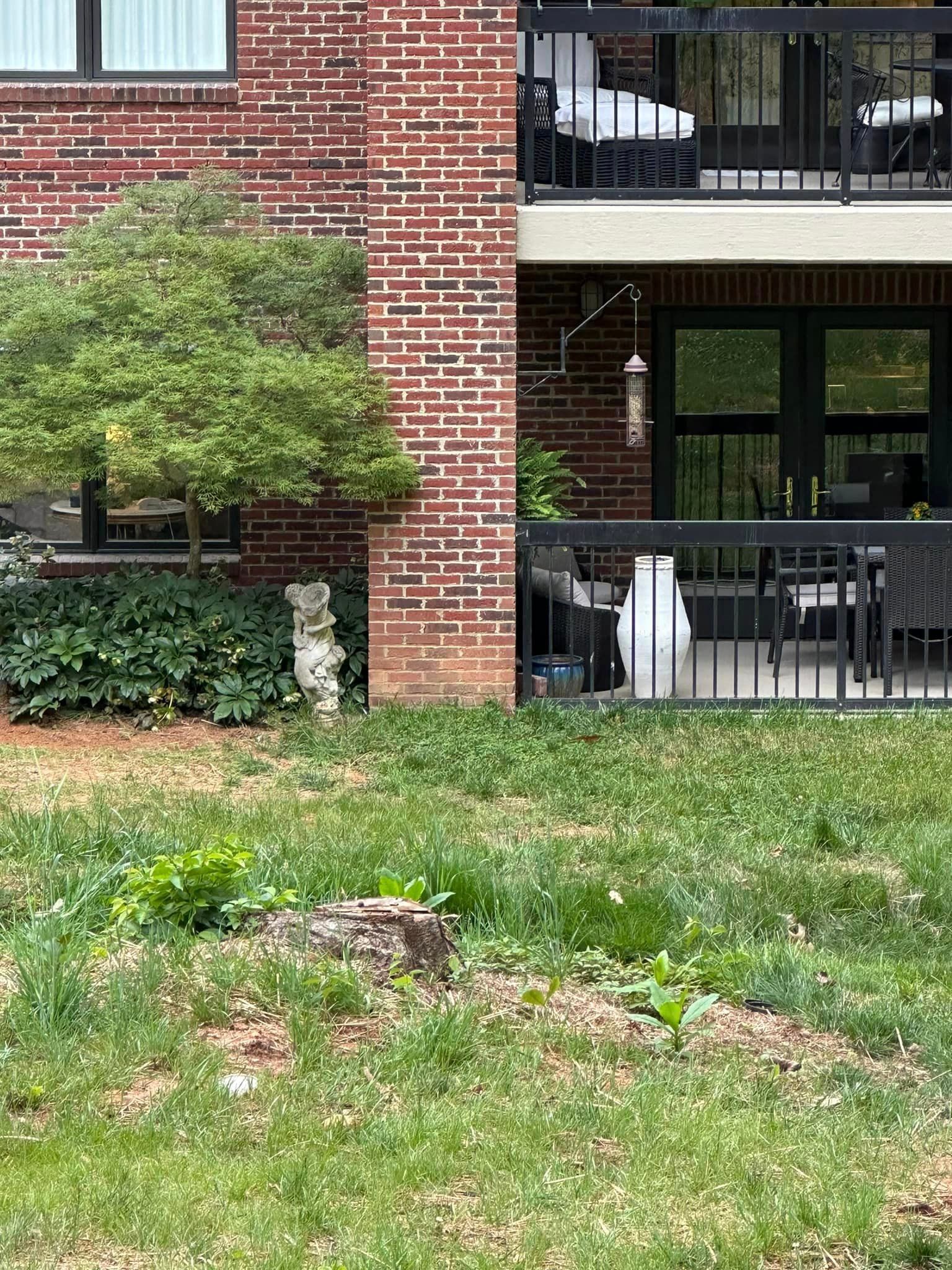 A brick building with a balcony and a lawn in front of it.