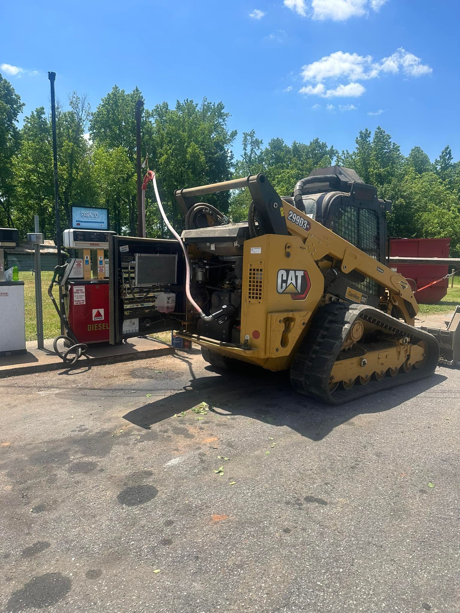 A bulldozer is parked in a parking lot next to a gas pump.