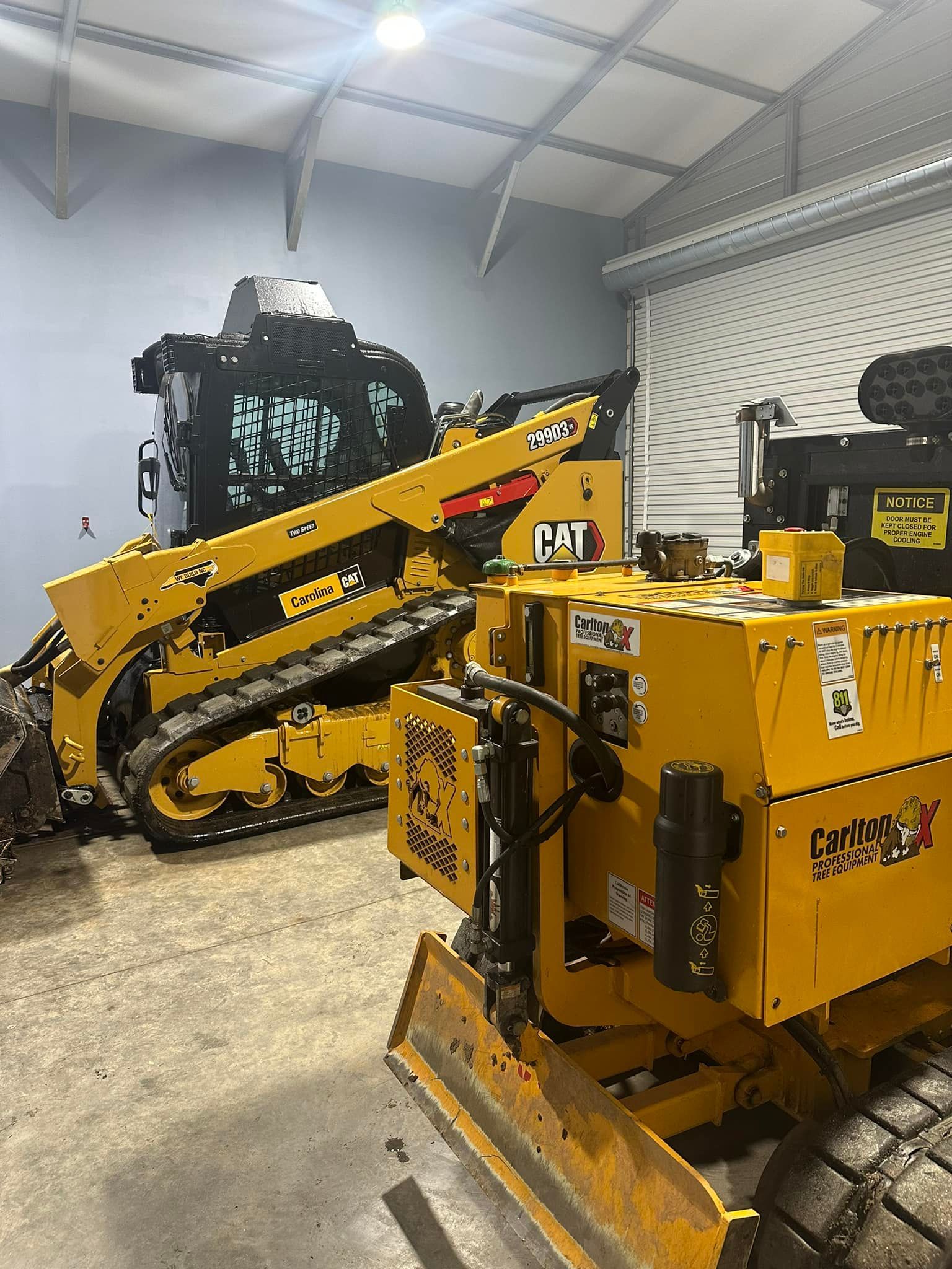 A couple of yellow tractors are parked in a garage.