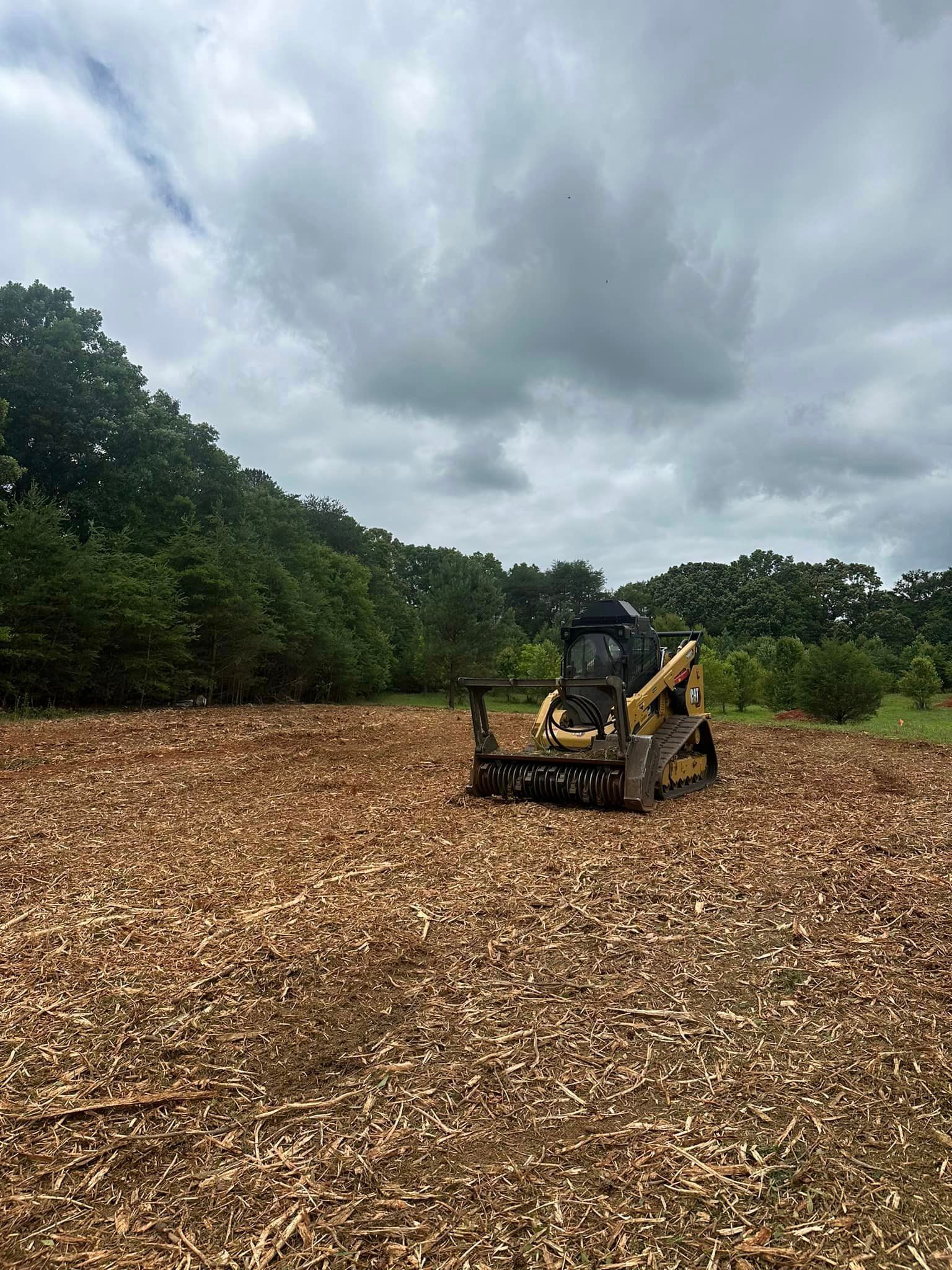 A bulldozer is sitting on top of a pile of wood chips in a field.
