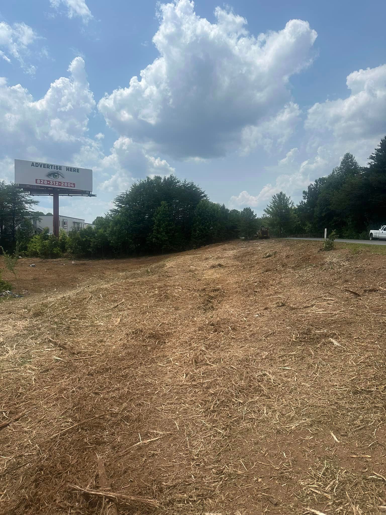 A large billboard is sitting on top of a dirt field.