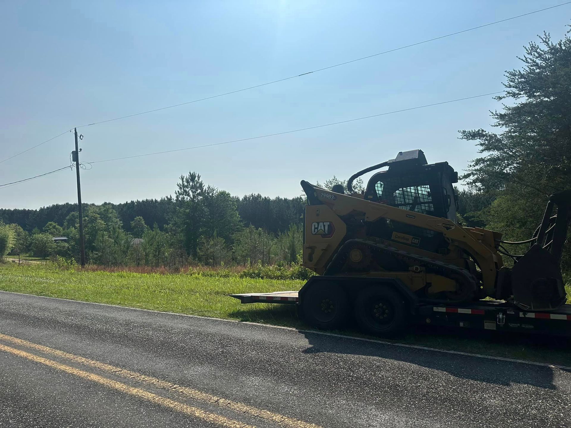 A cat skid steer is parked on the side of the road