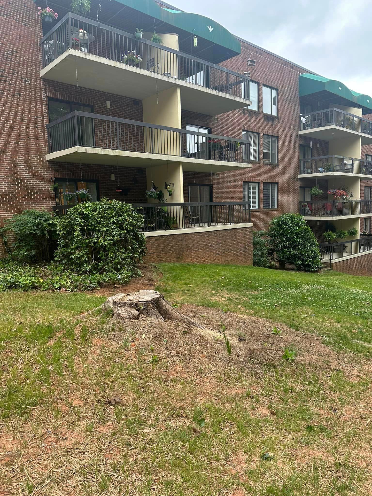 A large brick building with a lot of balconies and a large lawn in front of it.