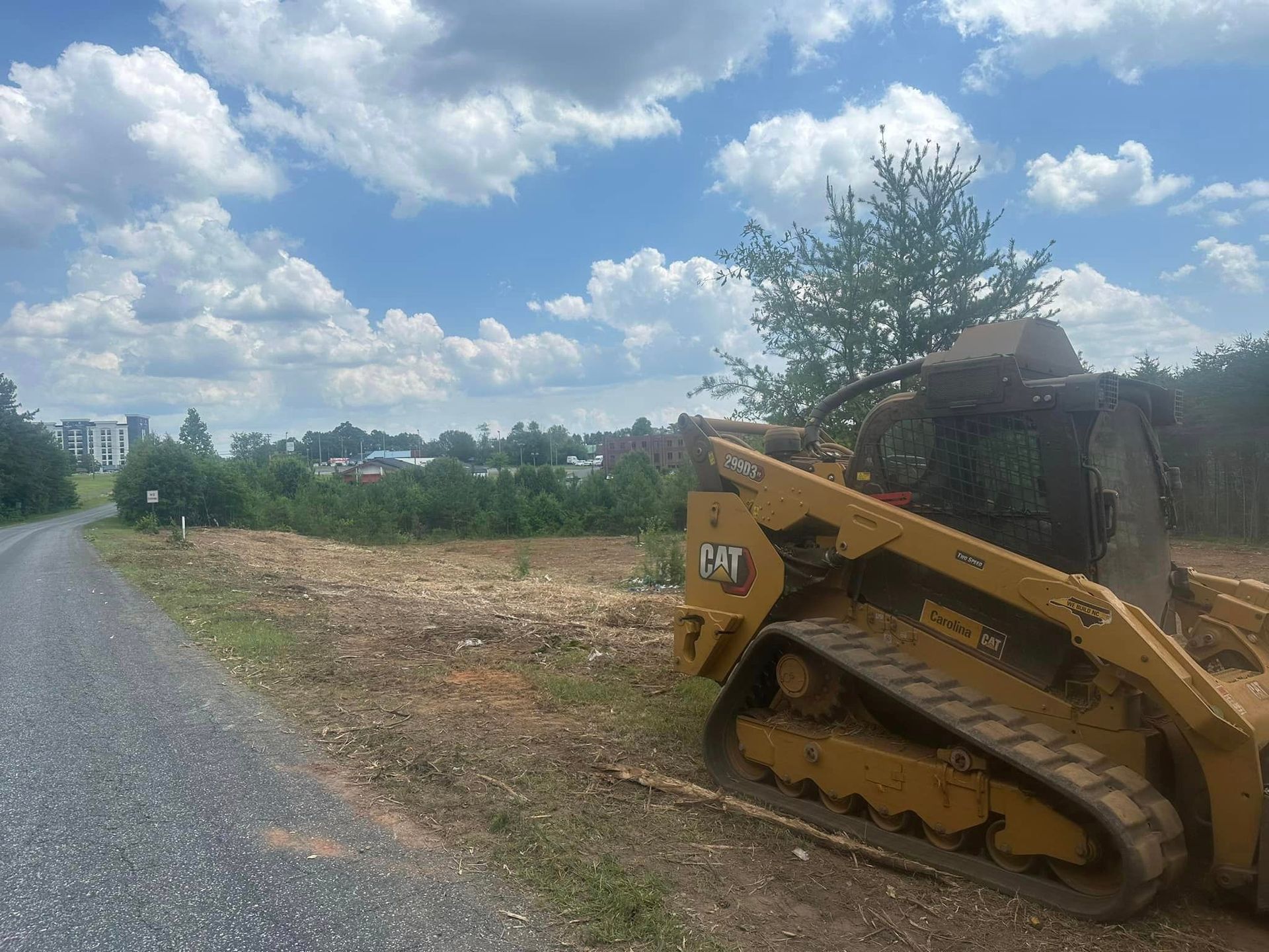 A bulldozer is parked on the side of the road in a field.