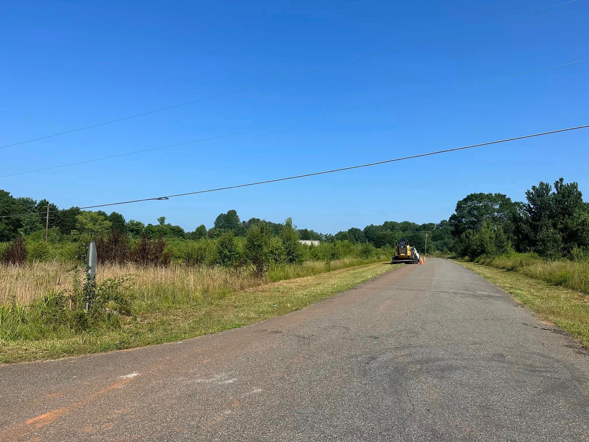 A truck is driving down a dirt road next to a field.