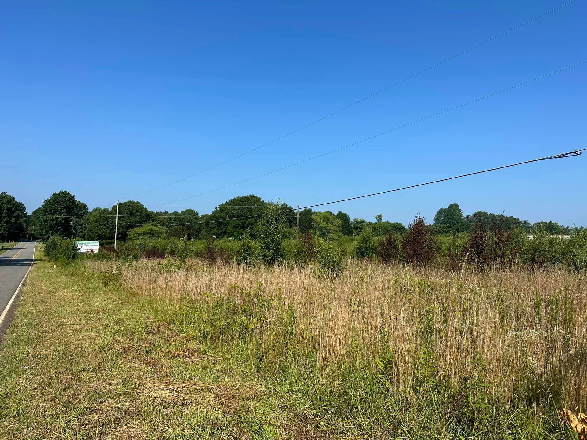 A field with a barbed wire fence and a road in the background.
