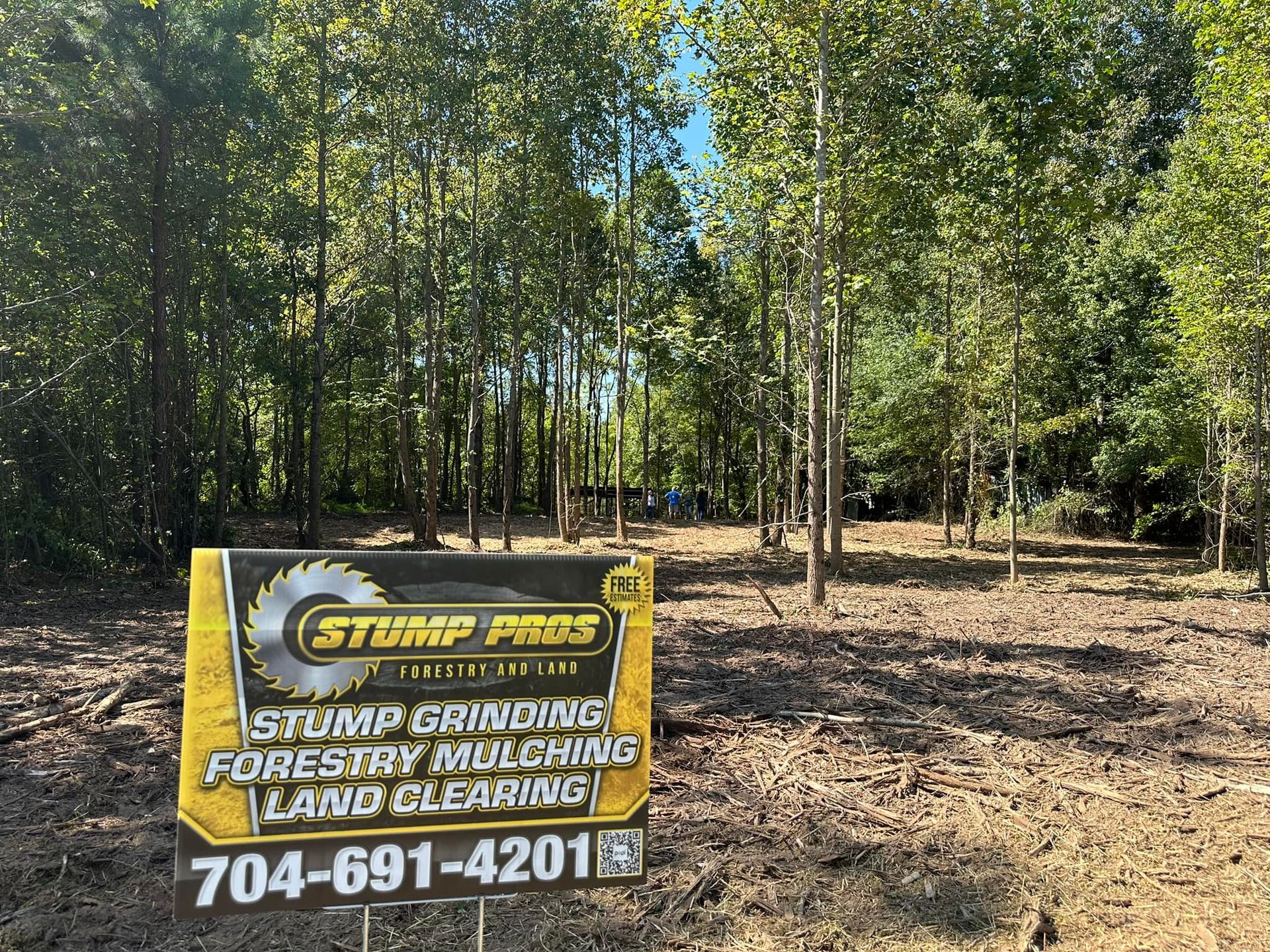 A yellow sign is sitting in the middle of a forest.