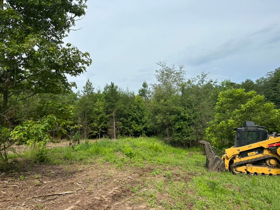 A bulldozer is sitting in a field with trees in the background.