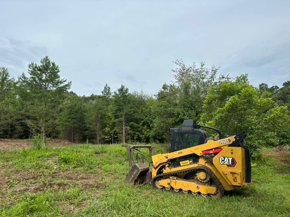 A yellow cat bulldozer is parked in a grassy field.