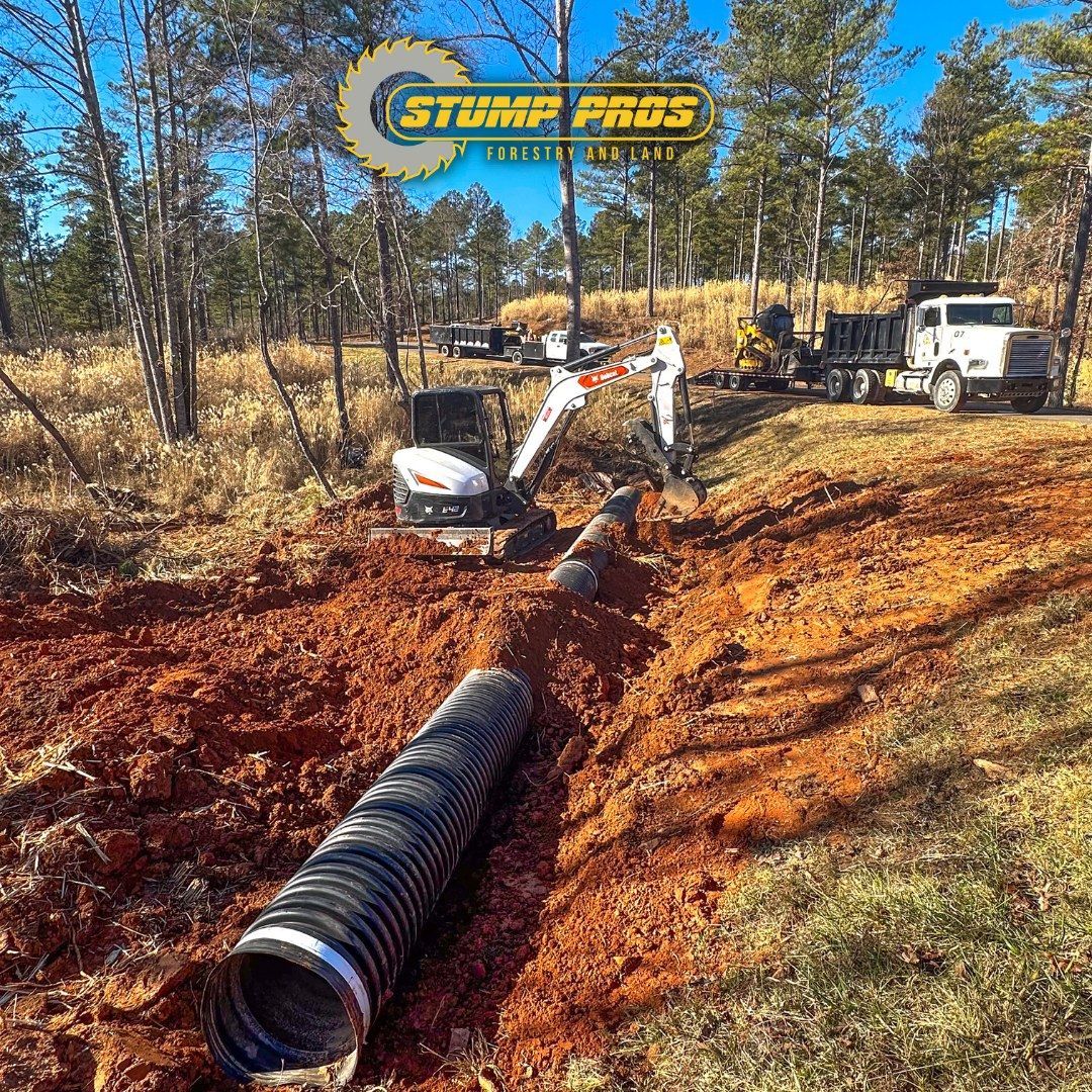 A large pipe is being installed in the dirt in a field.