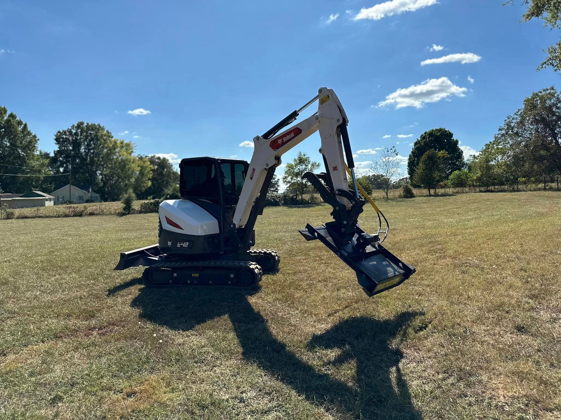 A small excavator is parked in a grassy field.