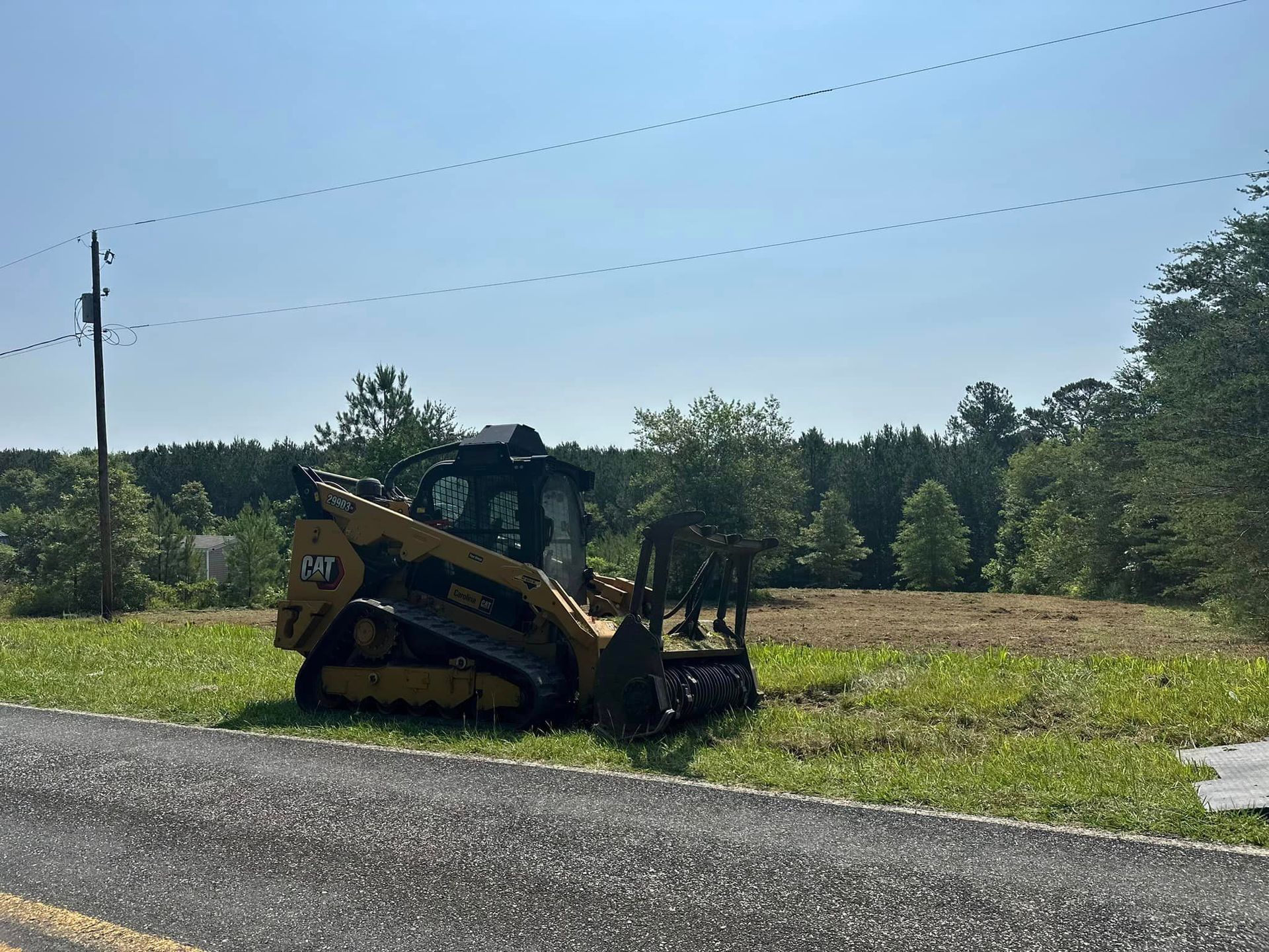 A bulldozer is parked on the side of the road in a field.