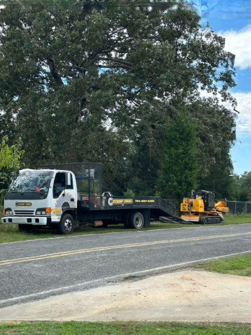 A tow truck is parked on the side of the road next to a bulldozer.