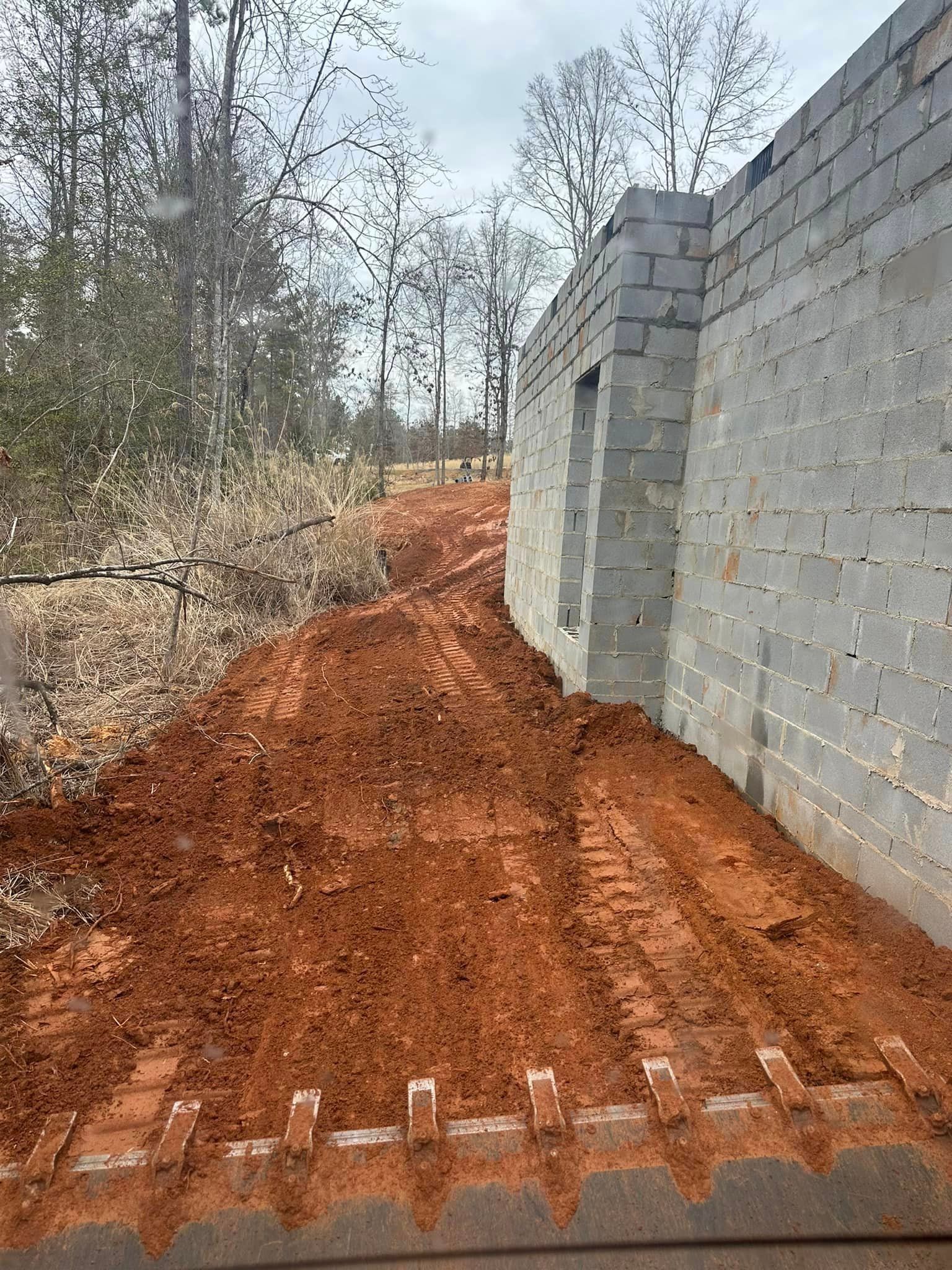 A brick wall is being built next to a dirt road.