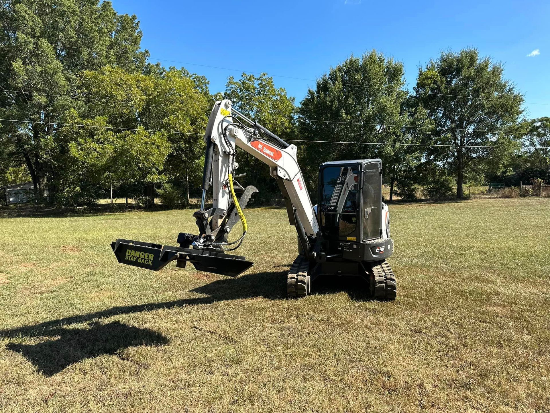 A small excavator is parked in a grassy field.