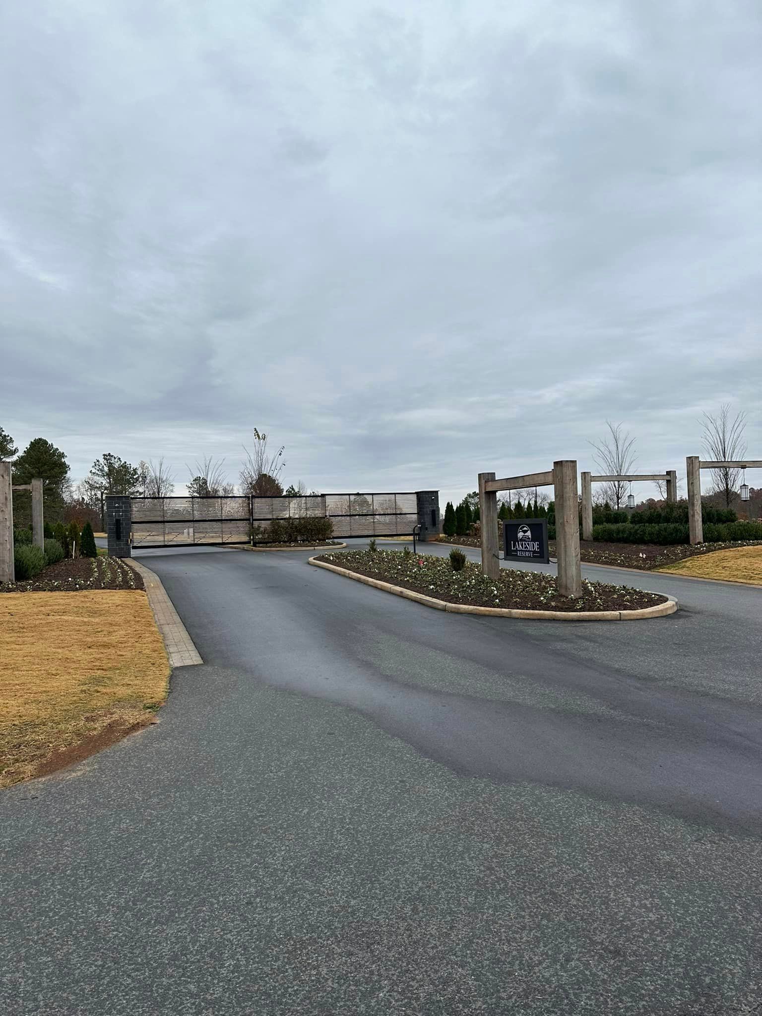 A driveway leading to a gated community with a wooden fence.