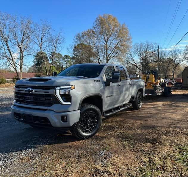 A silver truck is parked on the side of a dirt road.