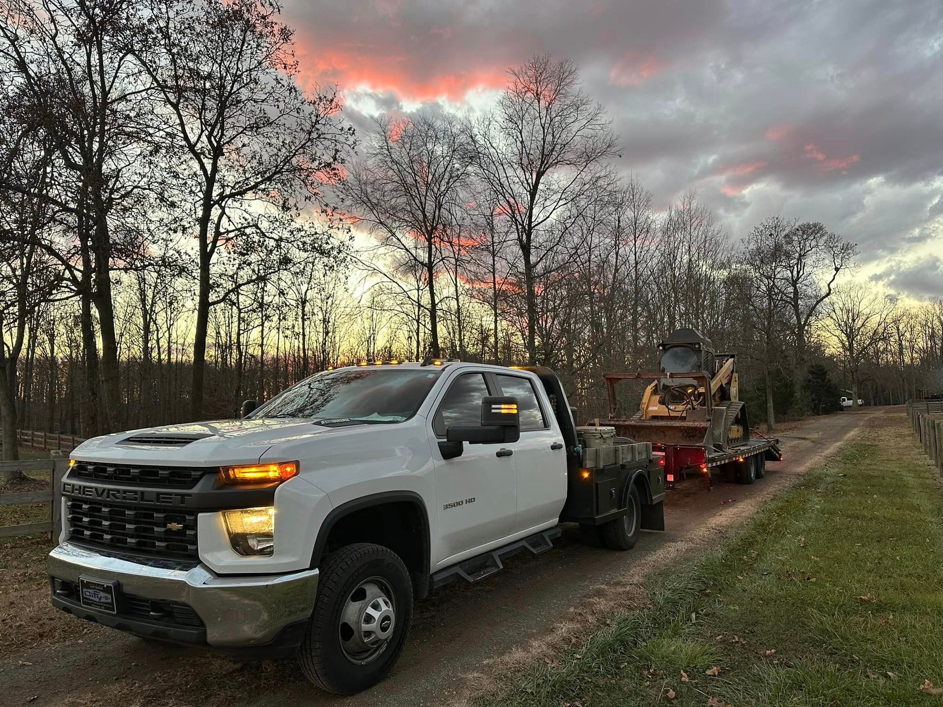 A white truck is towing a trailer with a bulldozer on it.