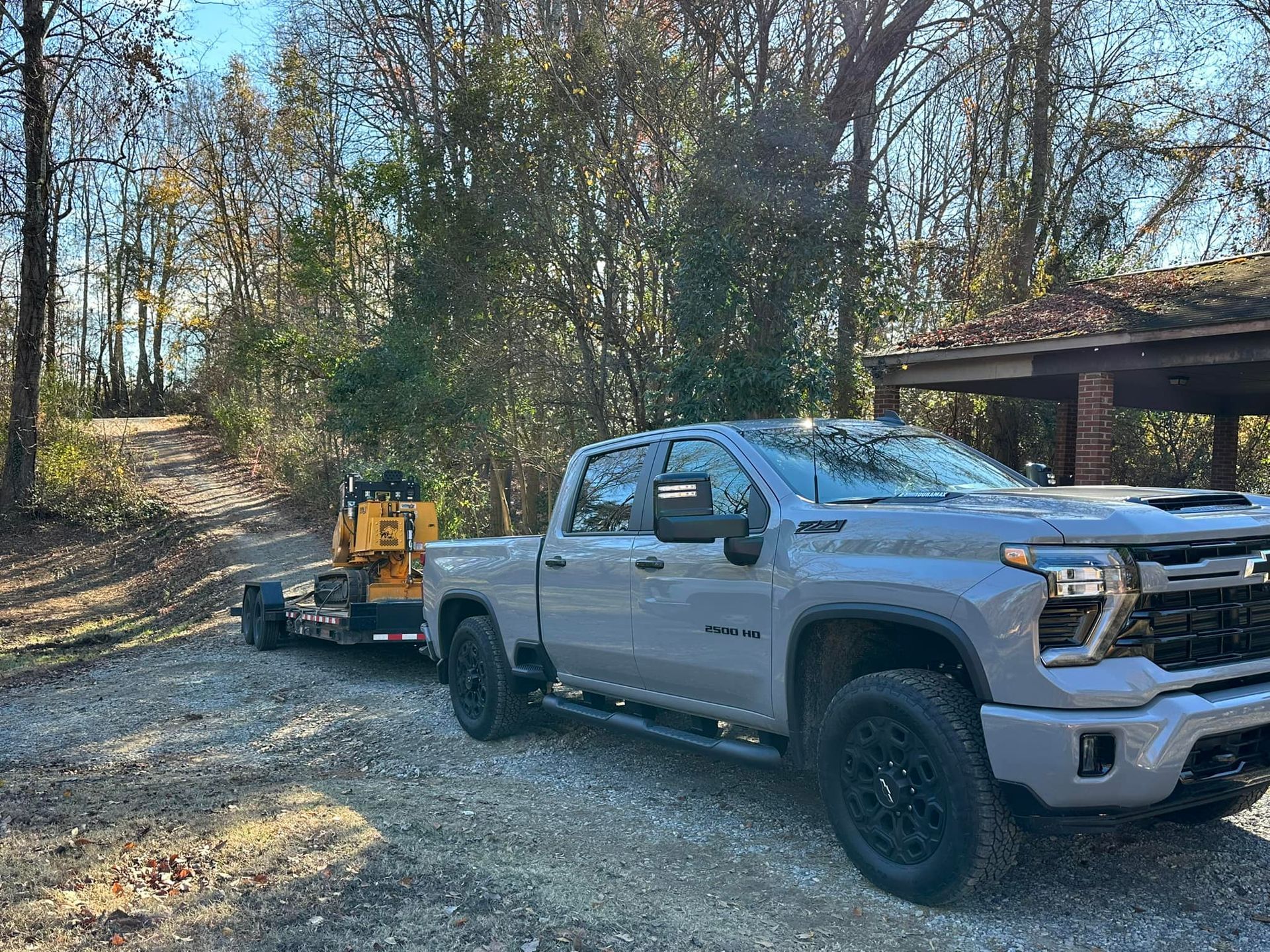 A truck with a trailer attached to it is parked on a gravel road.