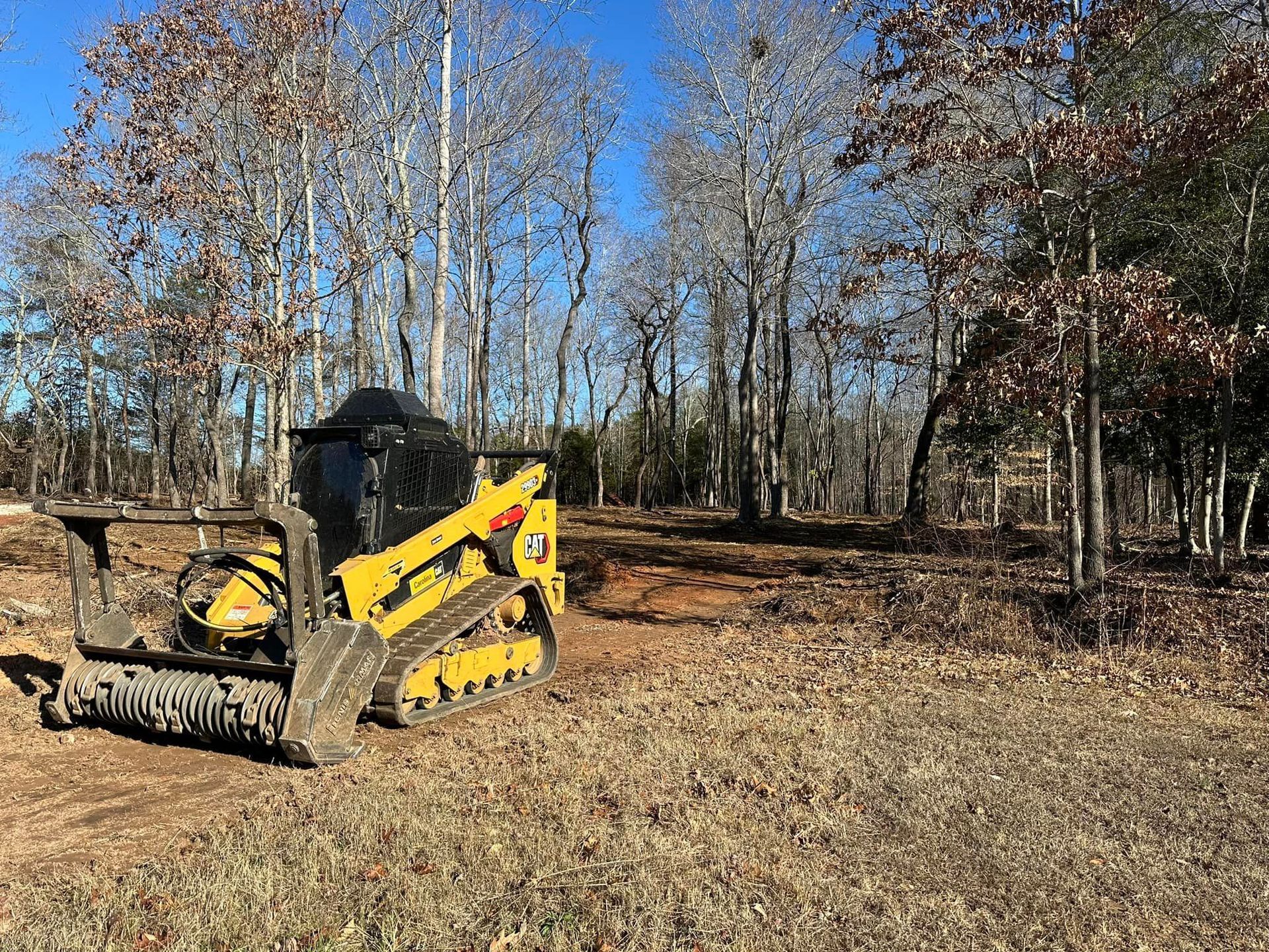 A yellow bulldozer is parked in a field with trees in the background.