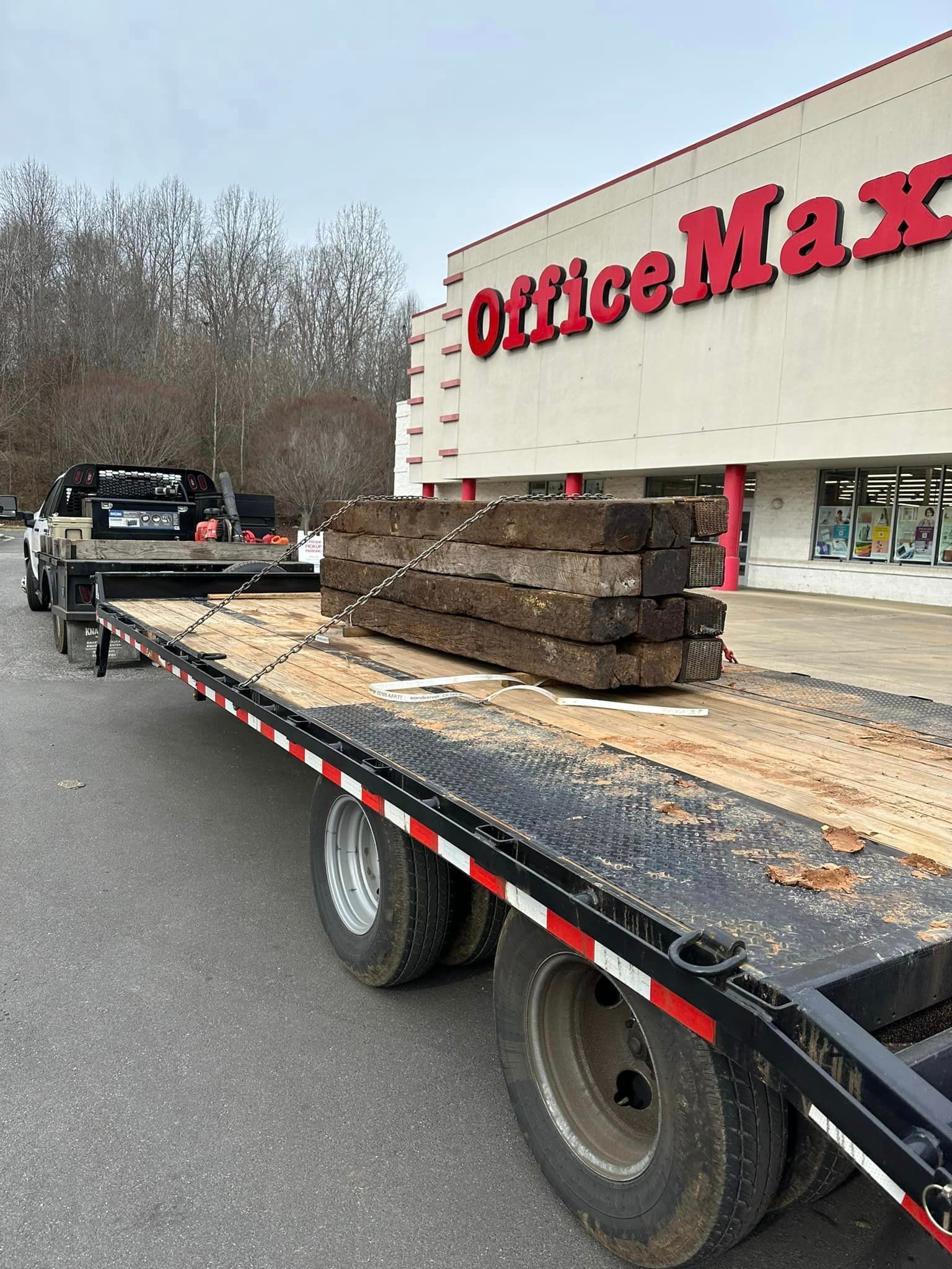 A flatbed truck is parked in front of an office max store.