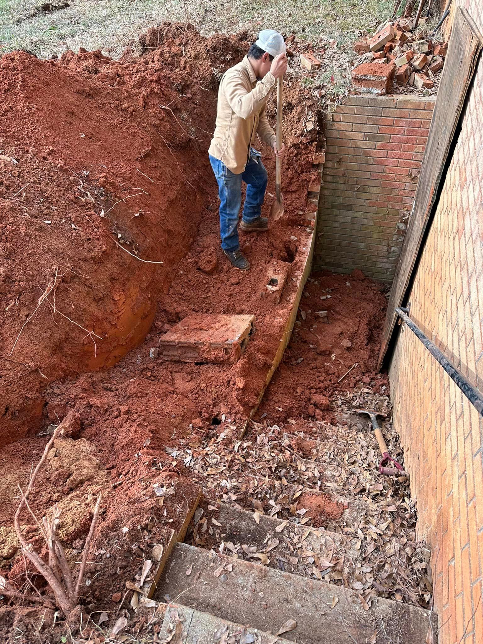 A man is digging a hole in the dirt with a shovel.