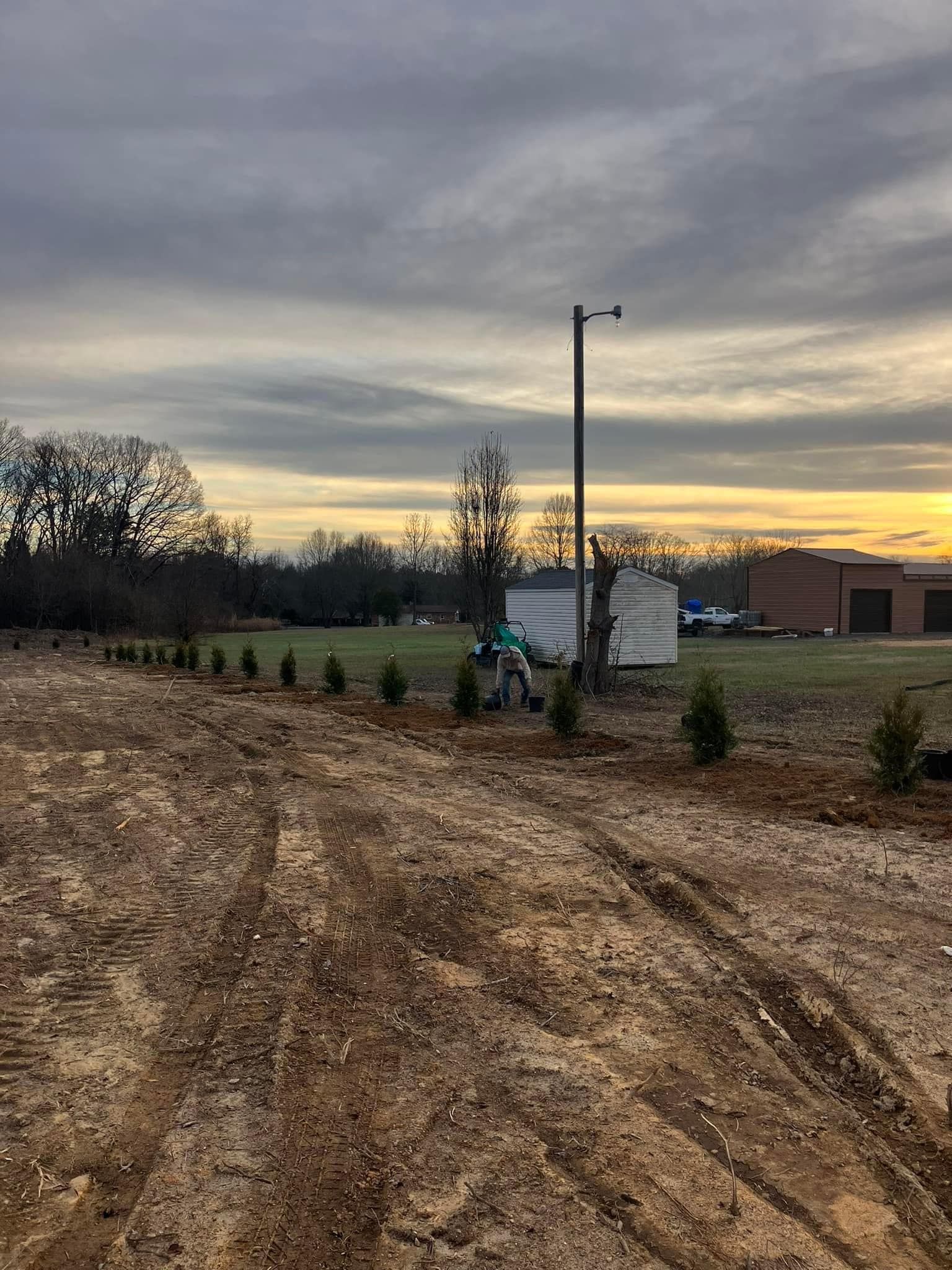 A dirt road leading to a building with a sunset in the background.