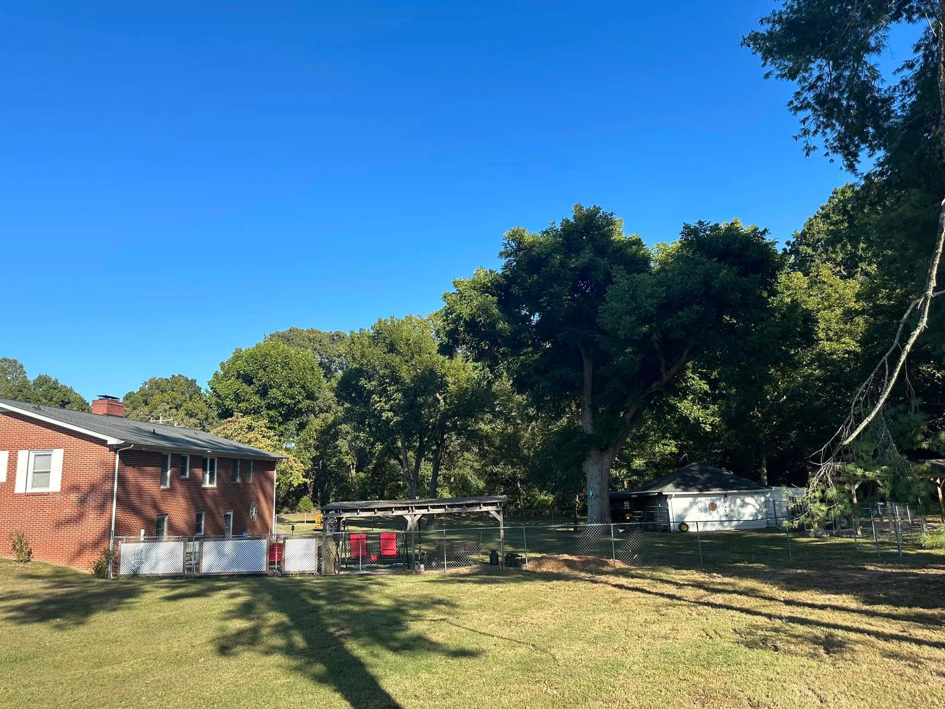 A brick house is sitting in the middle of a grassy yard surrounded by trees.