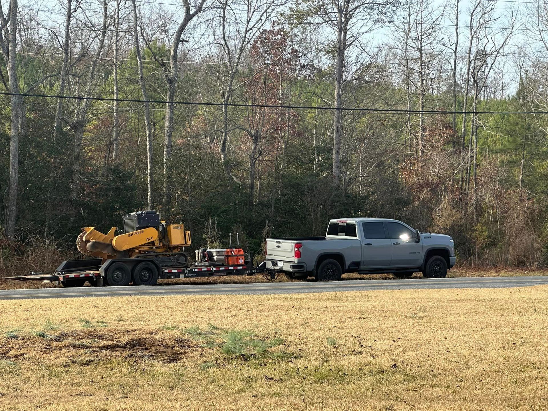 A truck is towing a trailer with a bulldozer on it.