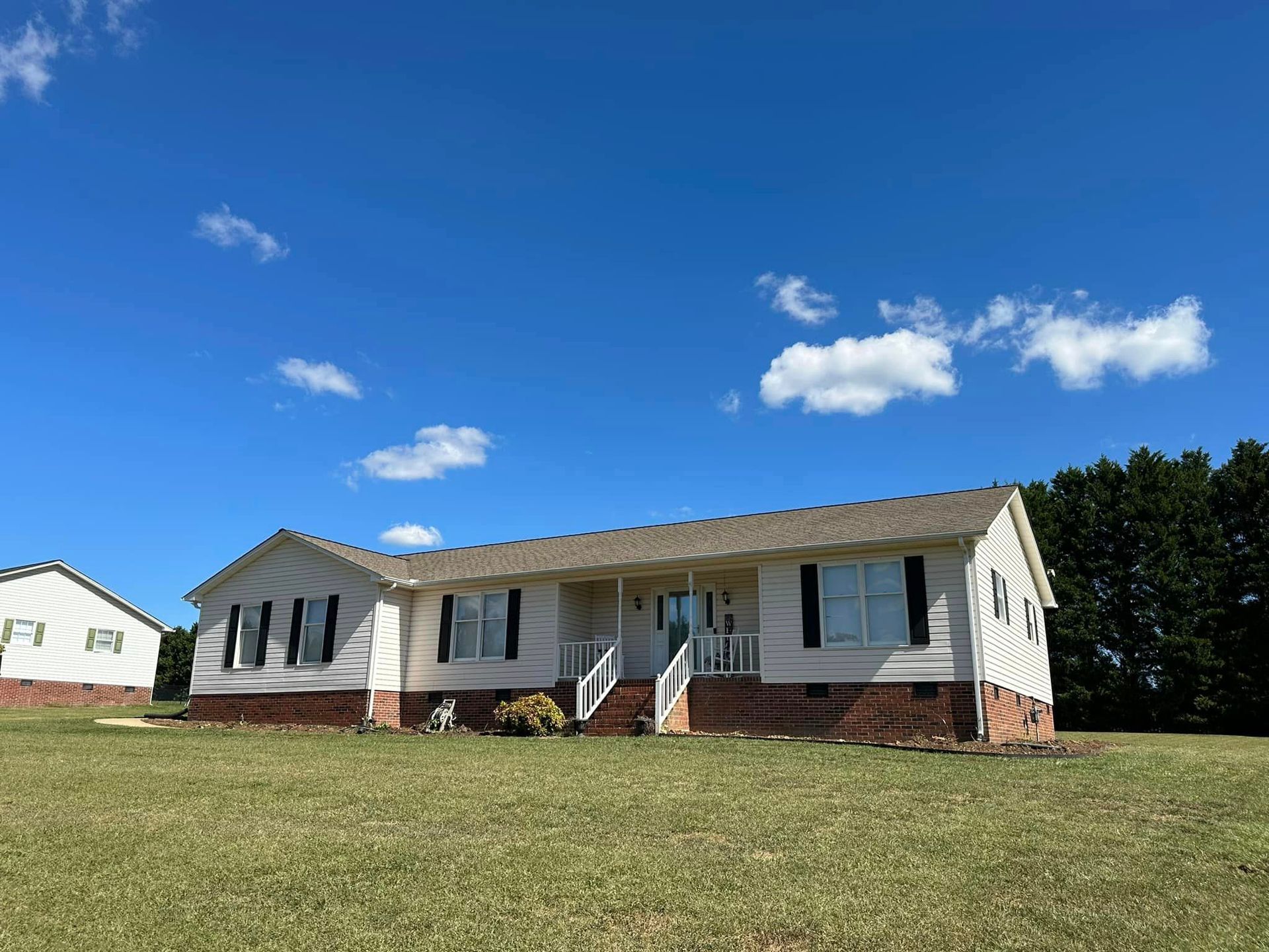 A white house is sitting on top of a lush green field.