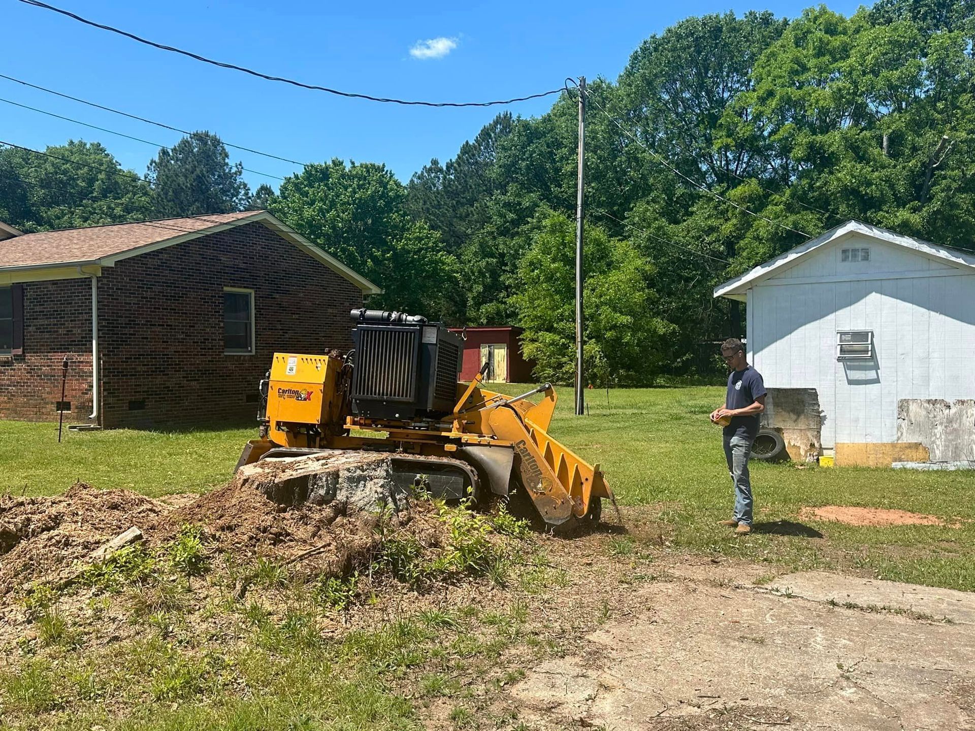 A man is standing next to a bulldozer in a yard.