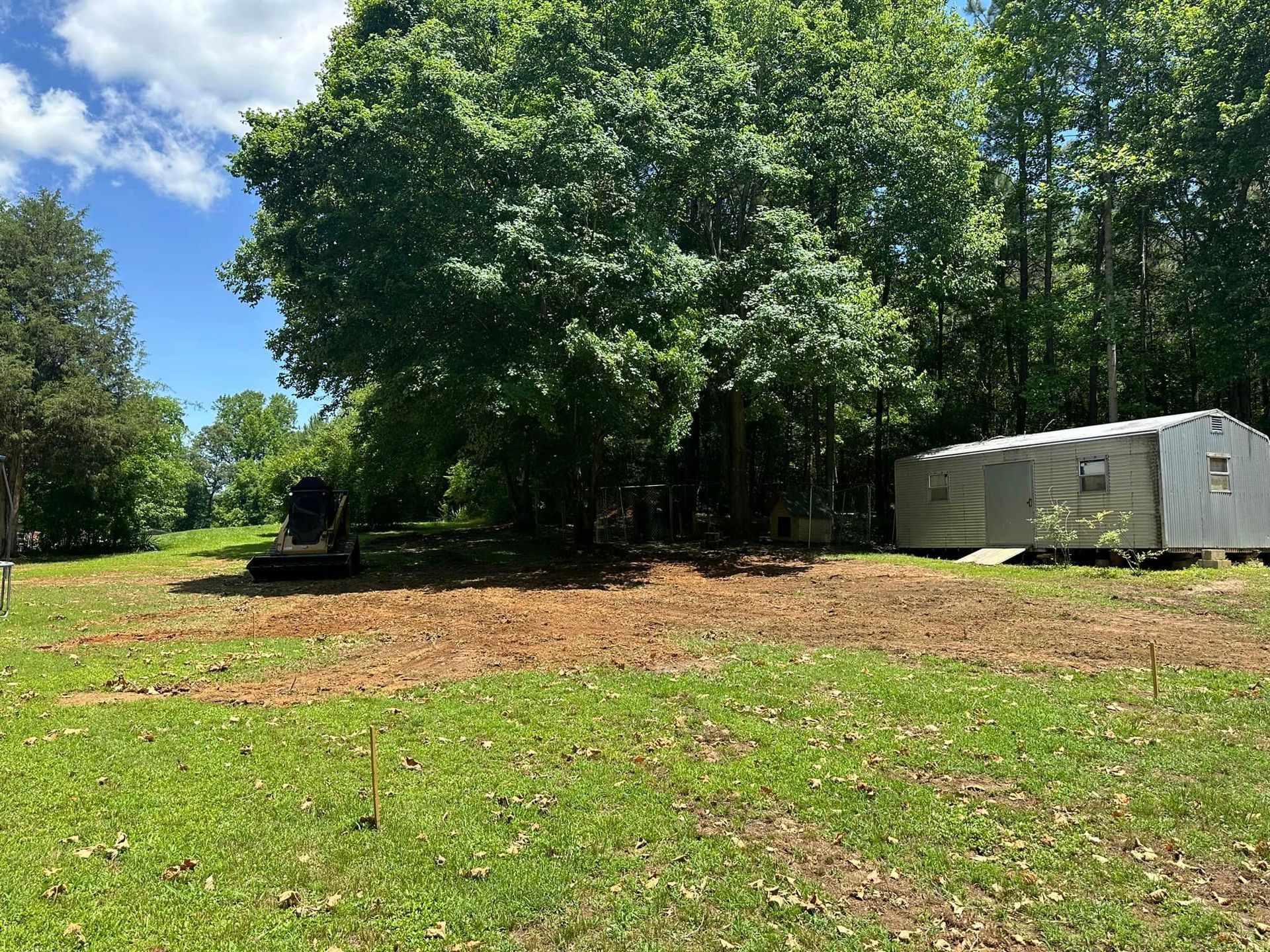 A trailer is parked in a grassy field next to a tree.