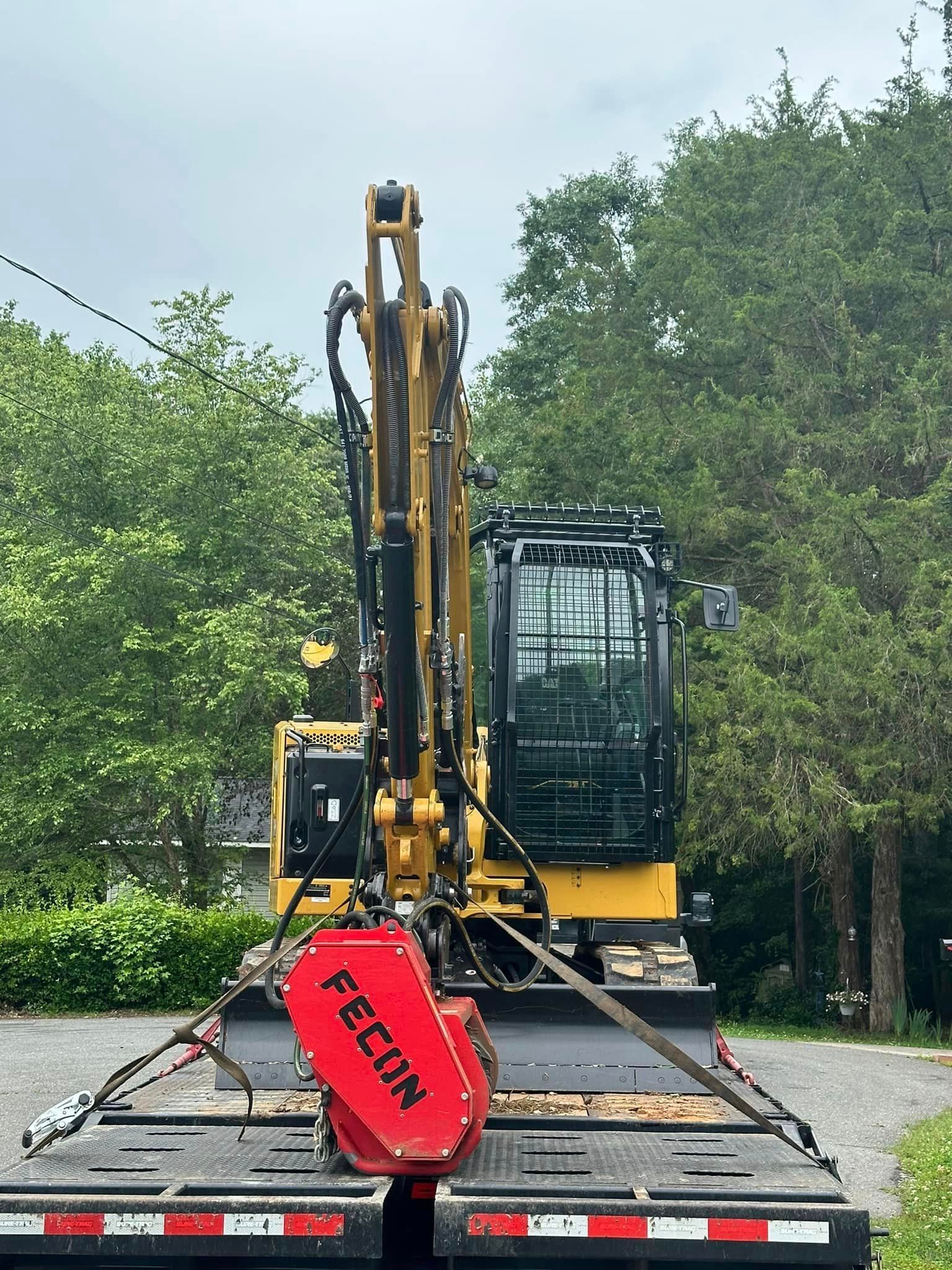 A yellow excavator is sitting on top of a trailer.
