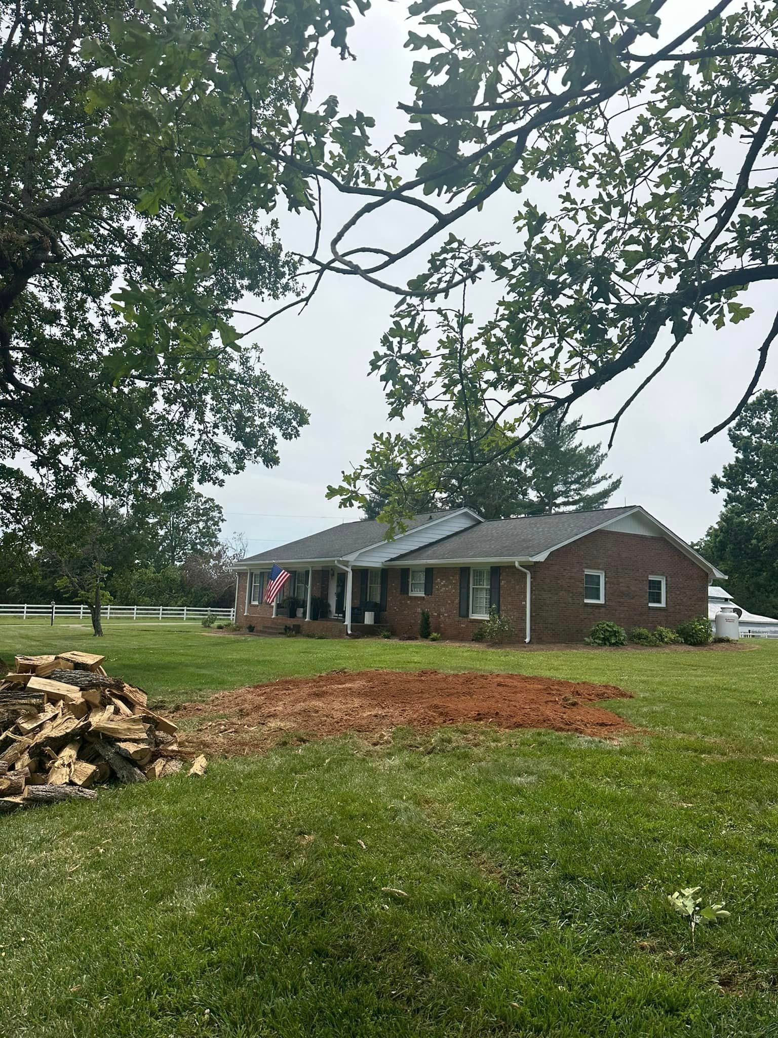 A brick house is sitting in the middle of a lush green field.