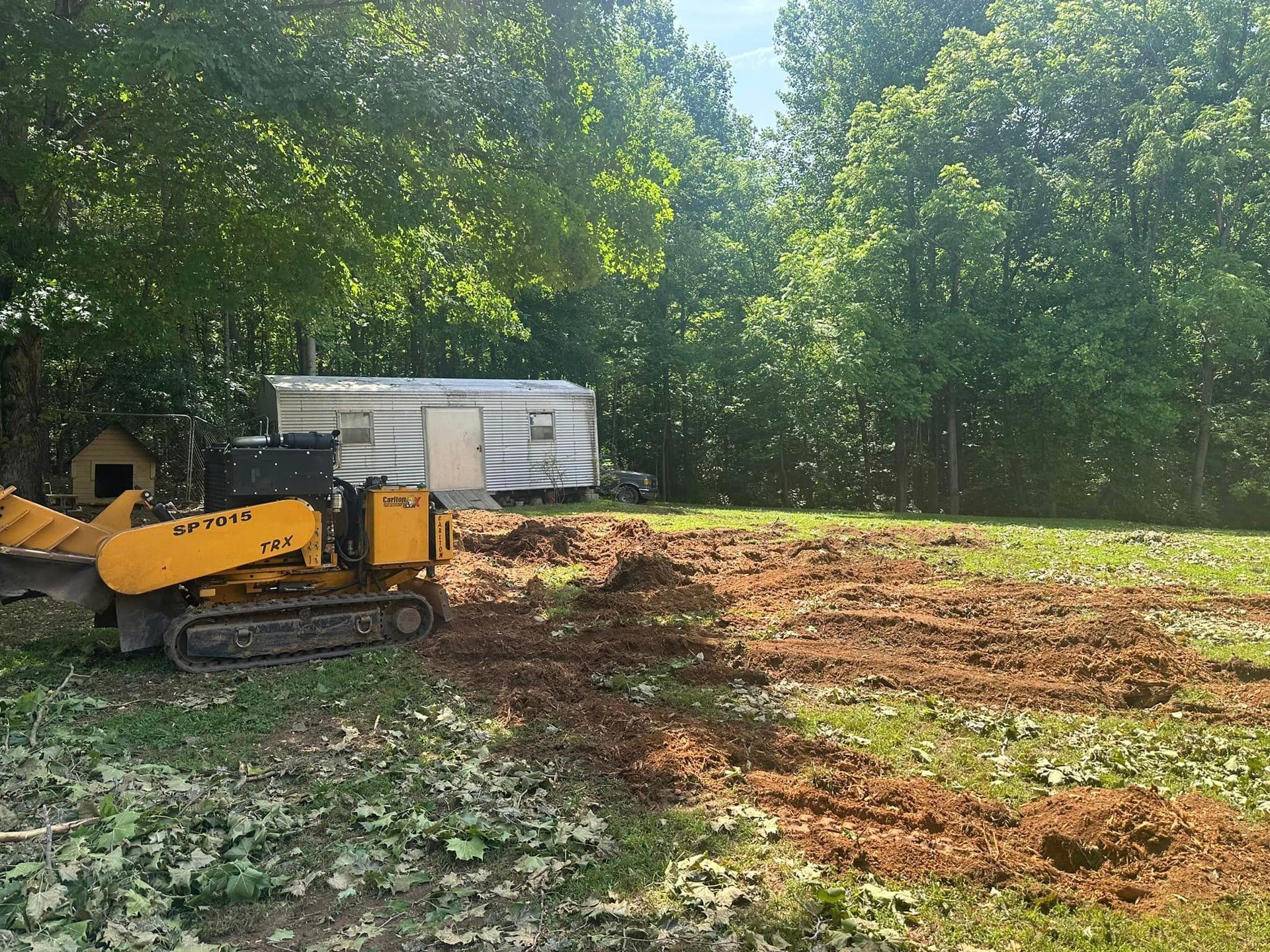 A yellow tractor is sitting in the middle of a dirt field.