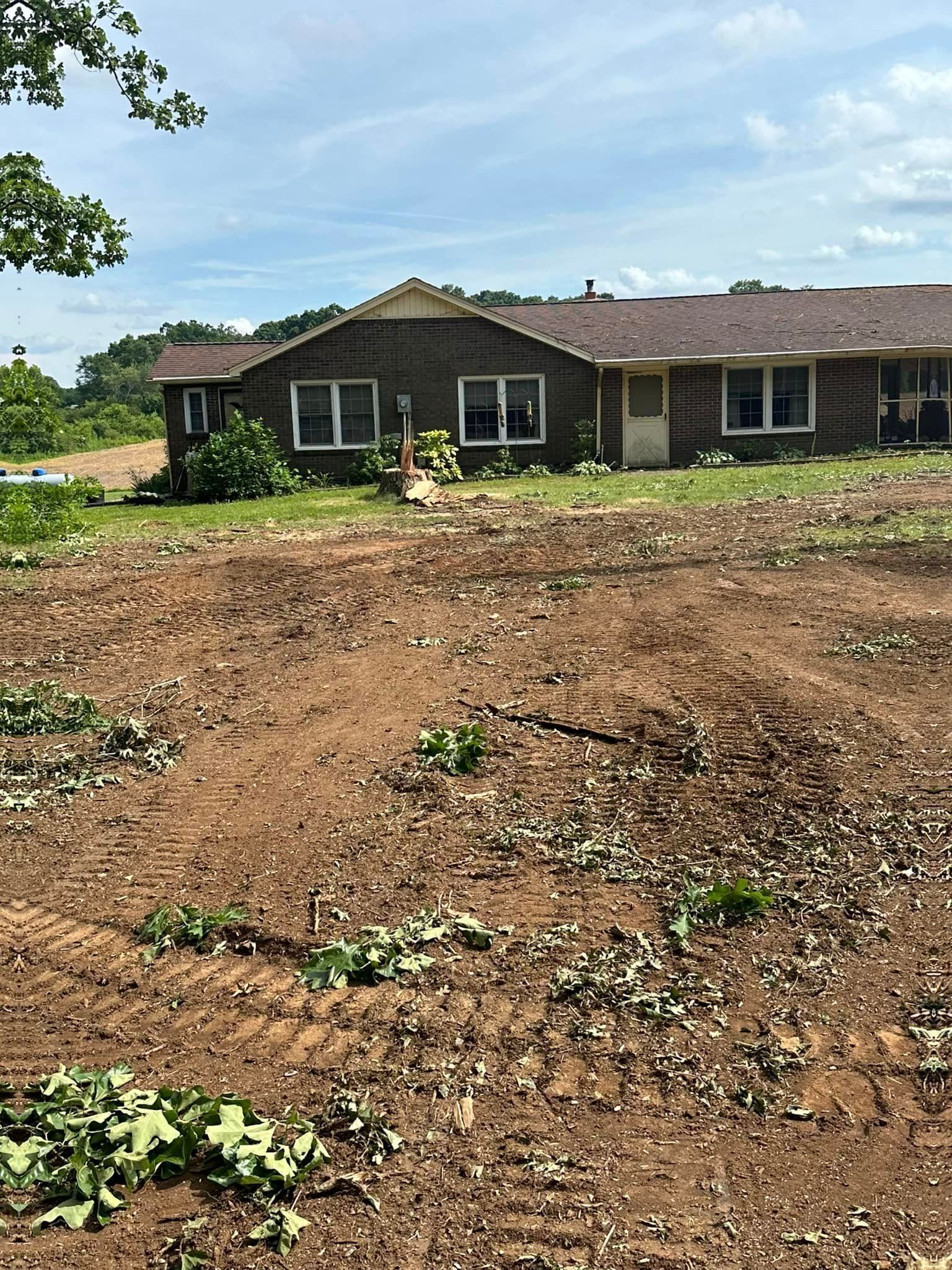 A house is sitting in the middle of a dirt field.