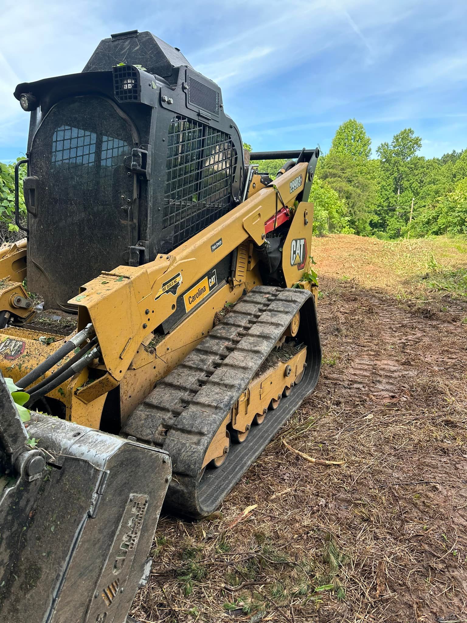 A bulldozer is parked in a field with trees in the background.