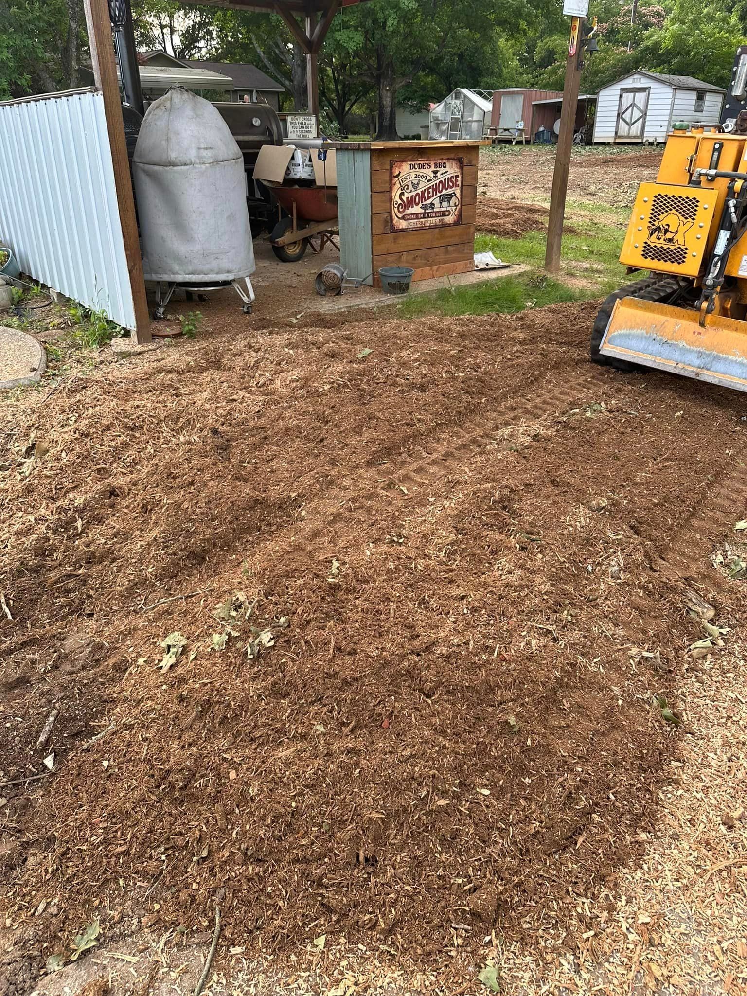 A stump grinder is sitting on top of a pile of wood chips in a yard.