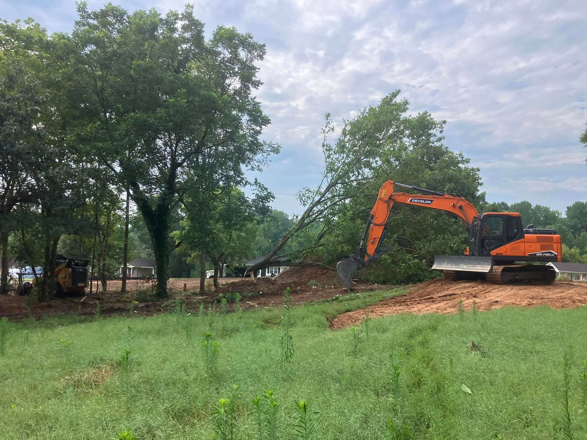 A large excavator is digging a hole in a grassy field.