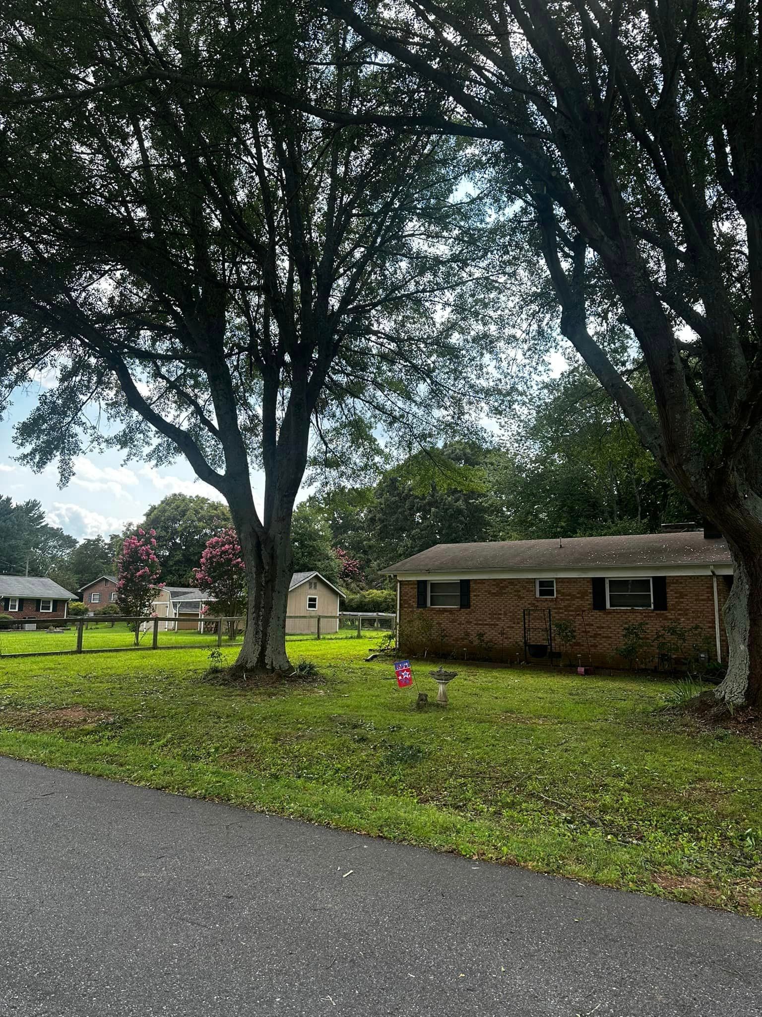 A house is sitting in the middle of a lush green field surrounded by trees.