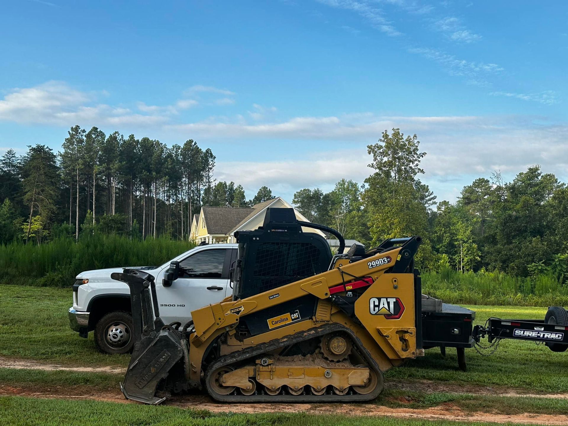 A bulldozer is parked next to a white truck in a field.