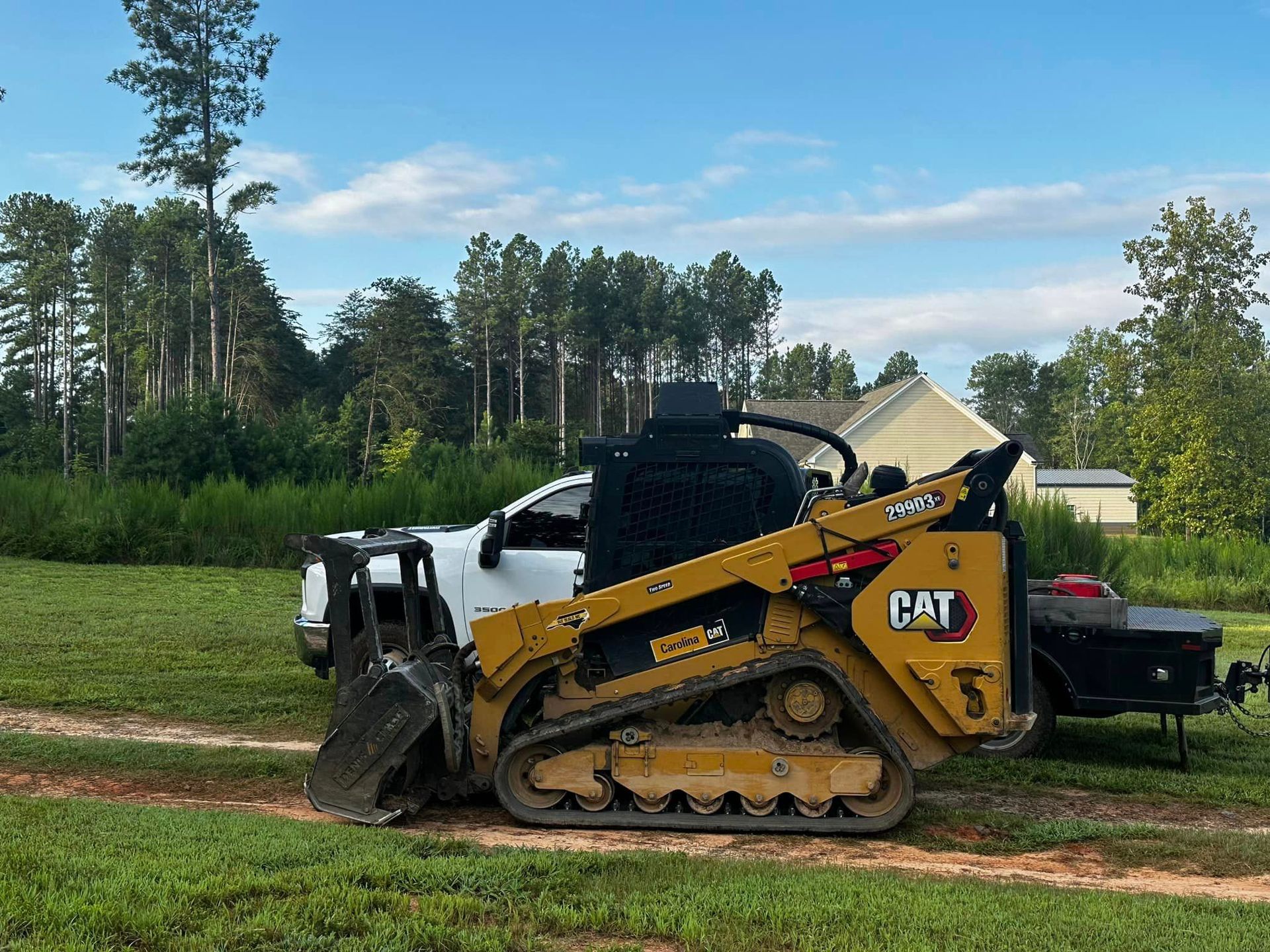 A bulldozer is parked next to a truck in a grassy field.