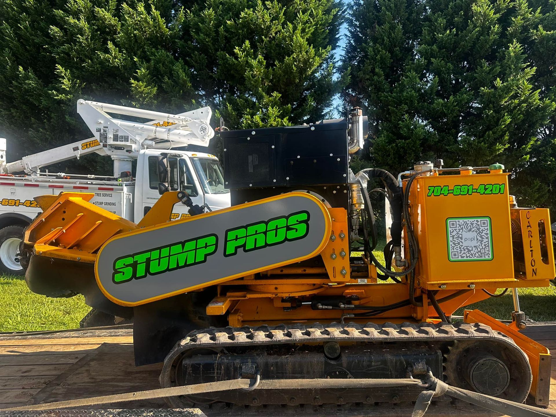 A yellow stump pros machine is parked in the dirt